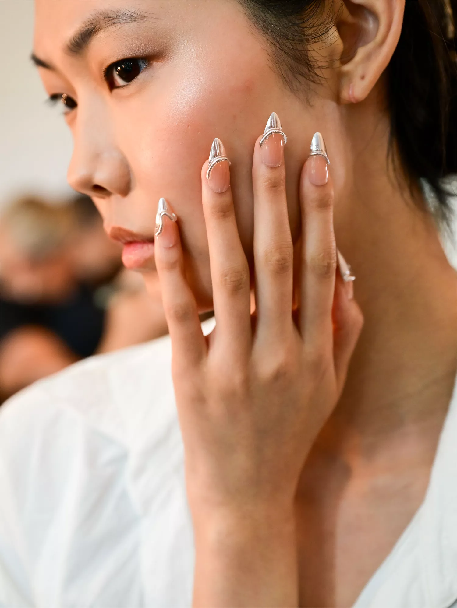 A woman wearing Chrome Nails, one of the Spring 2024 nail trends