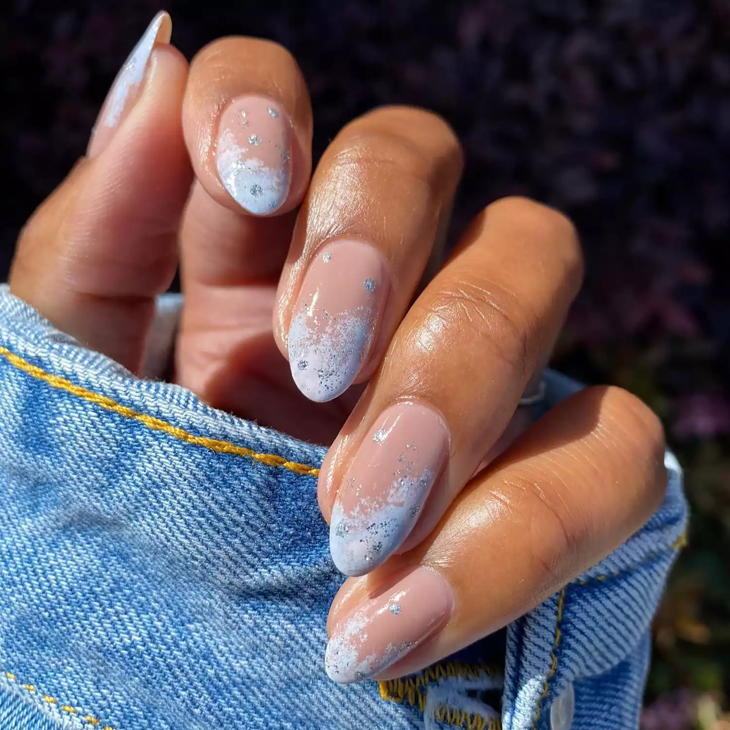 Close up of a manicure with snowy blue tips and sparkly silver dots