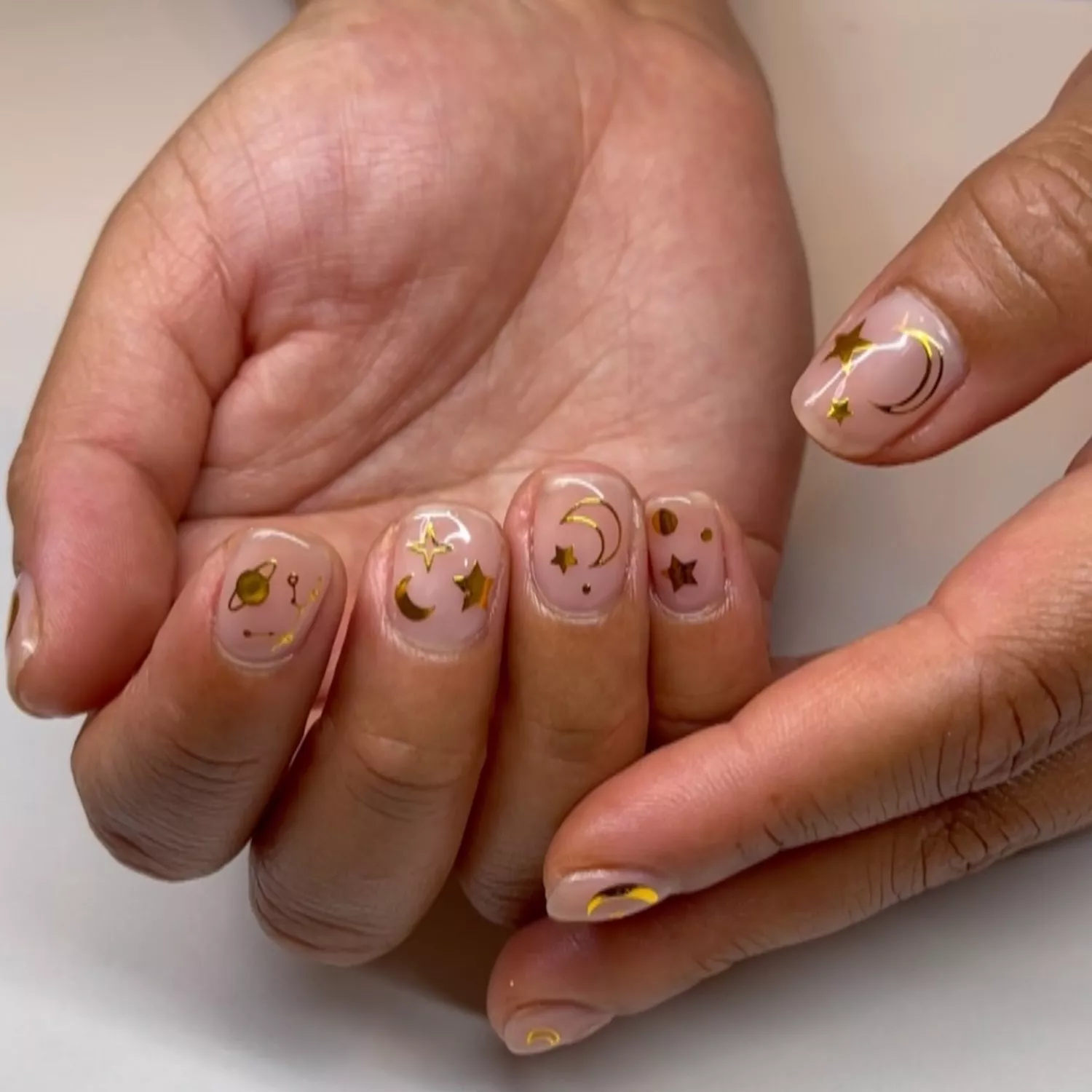 Clear manicure with gold star, moon, and planet decals