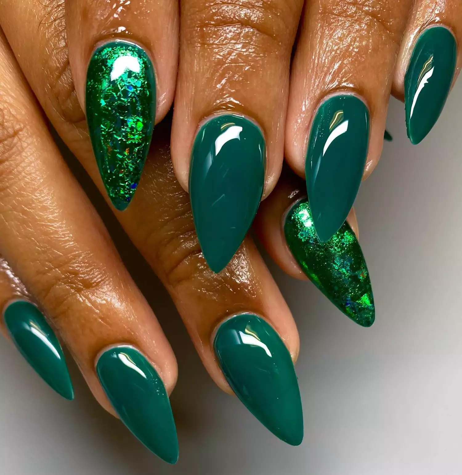 Close up of a pointed evergreen manicure with shimmery accent nails