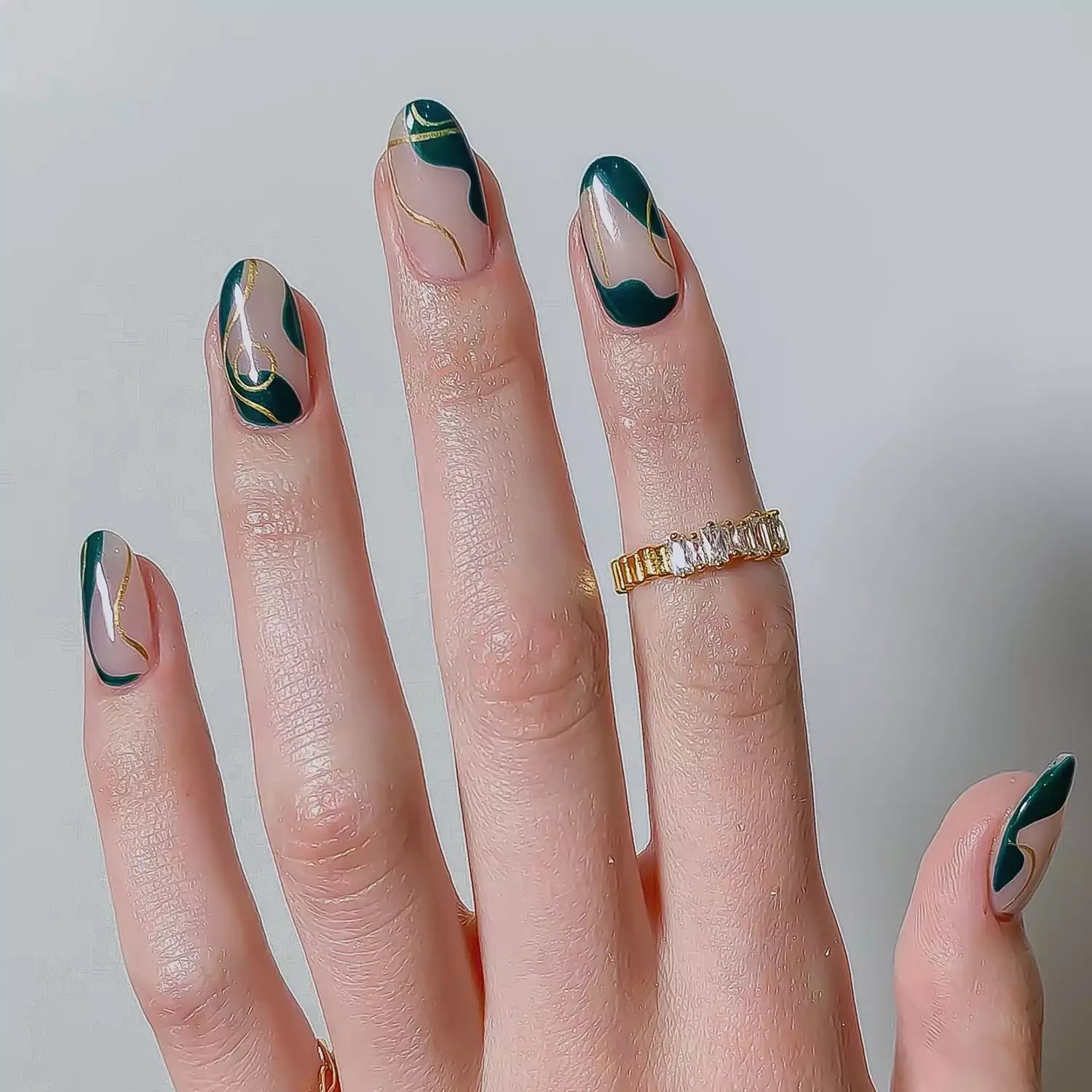 Close up of a negative space manicure with green and gold swirls