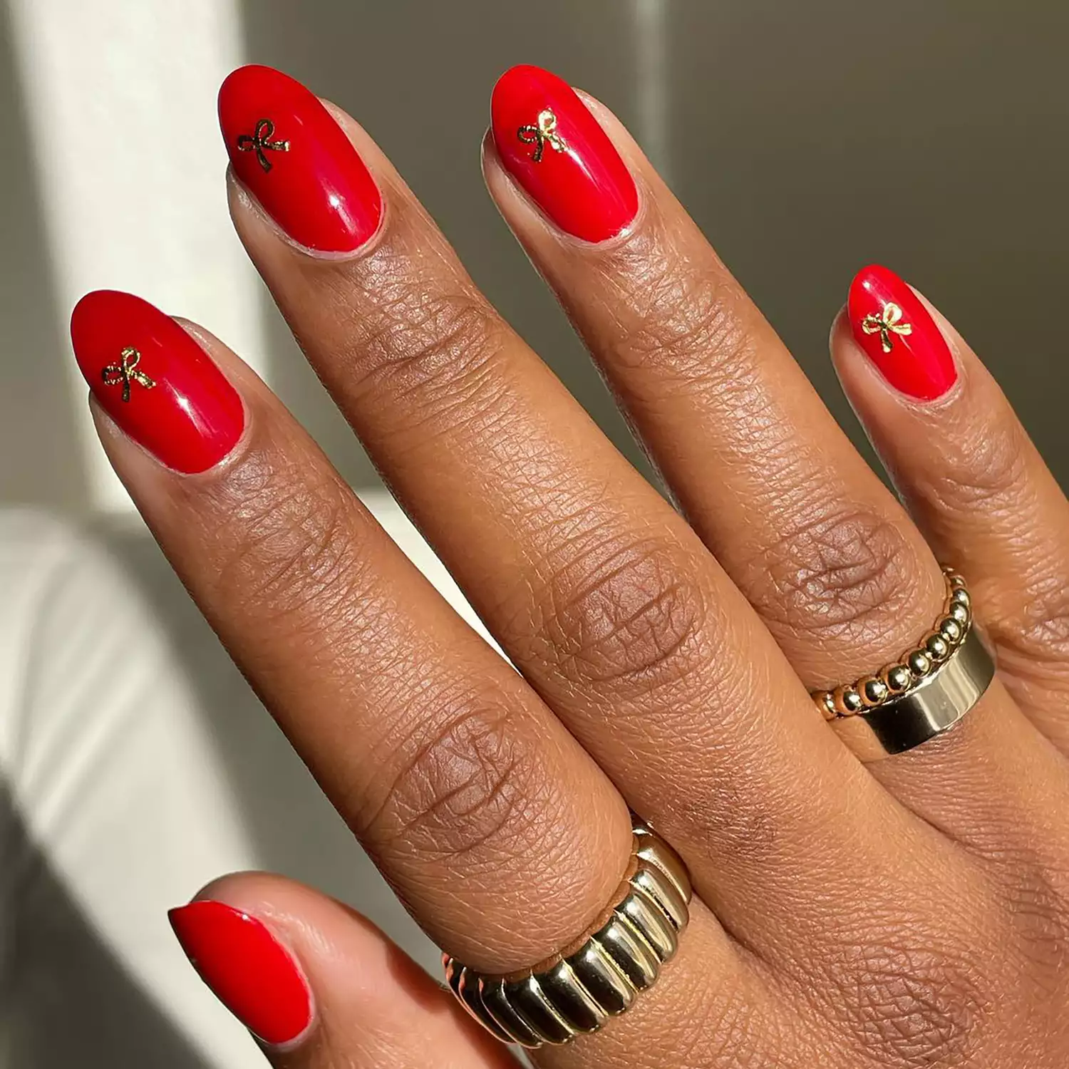 Close up of a red manicure with little gold bows