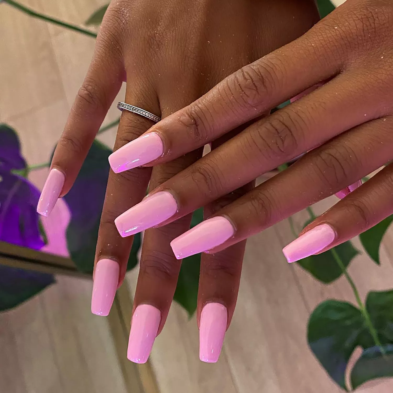 Close up of a medium-length baby pink manicure with square tips