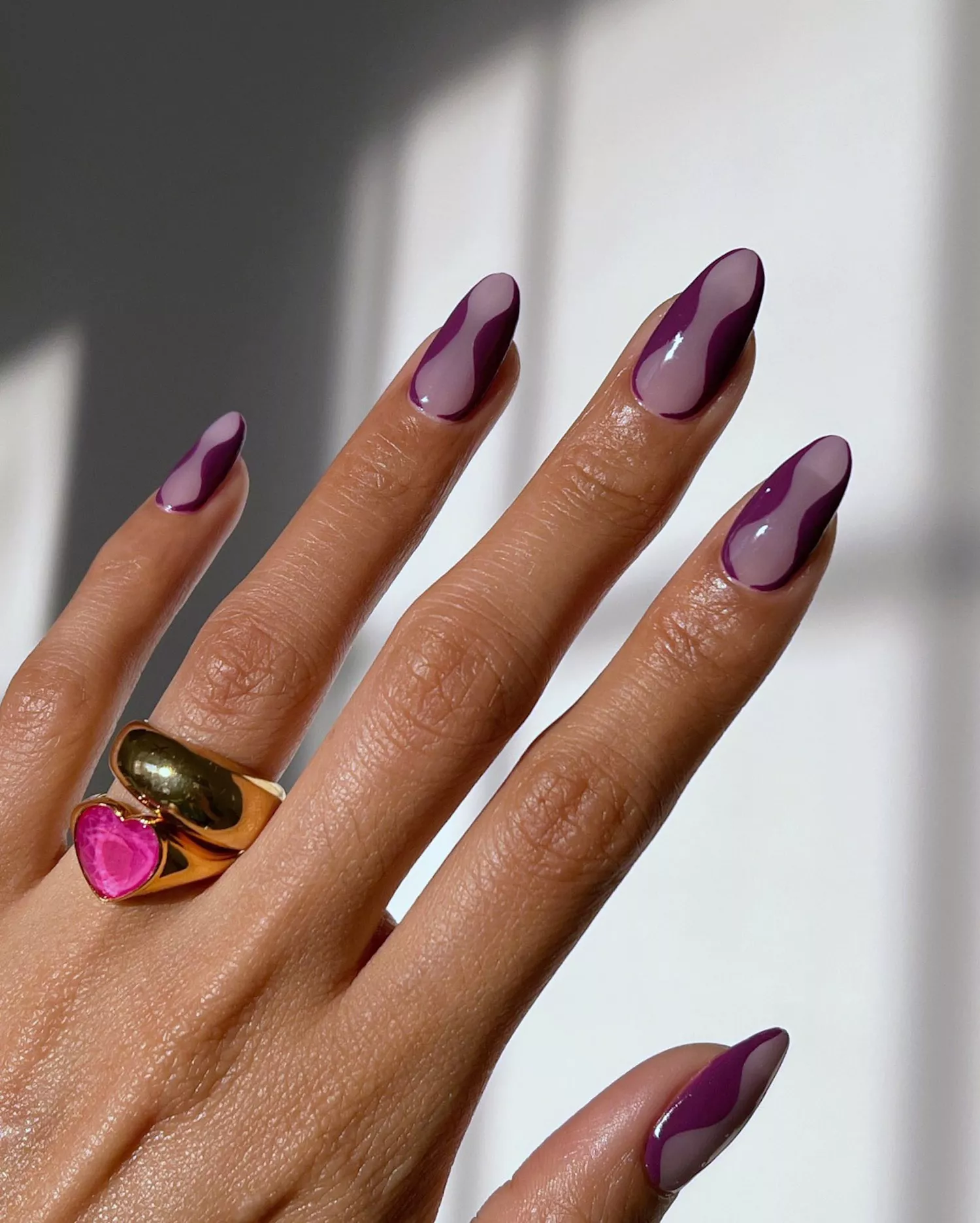 Close up of a swirly manicure in sheer and opaque purple shades