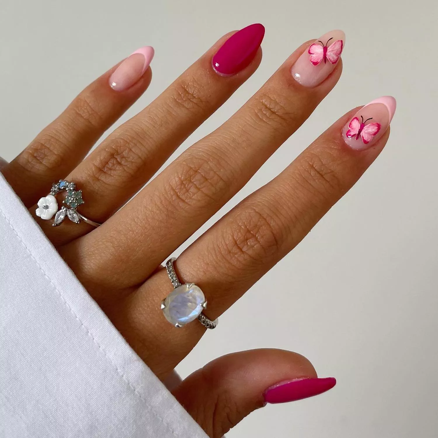 Manicure with solid hot pink nails and pastel pink French nails with pink butterfly designs