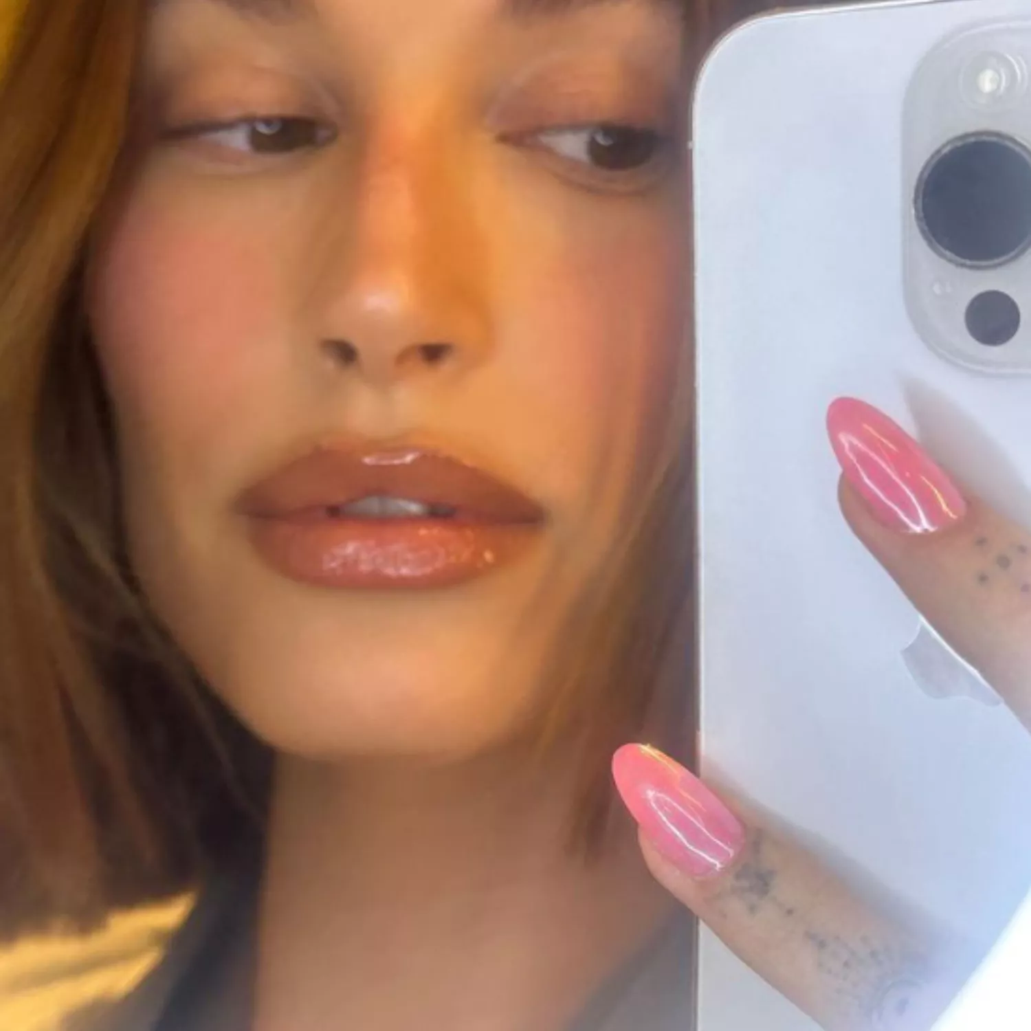 Hailey Bieber taking a selfie with Barbie glazed nails.