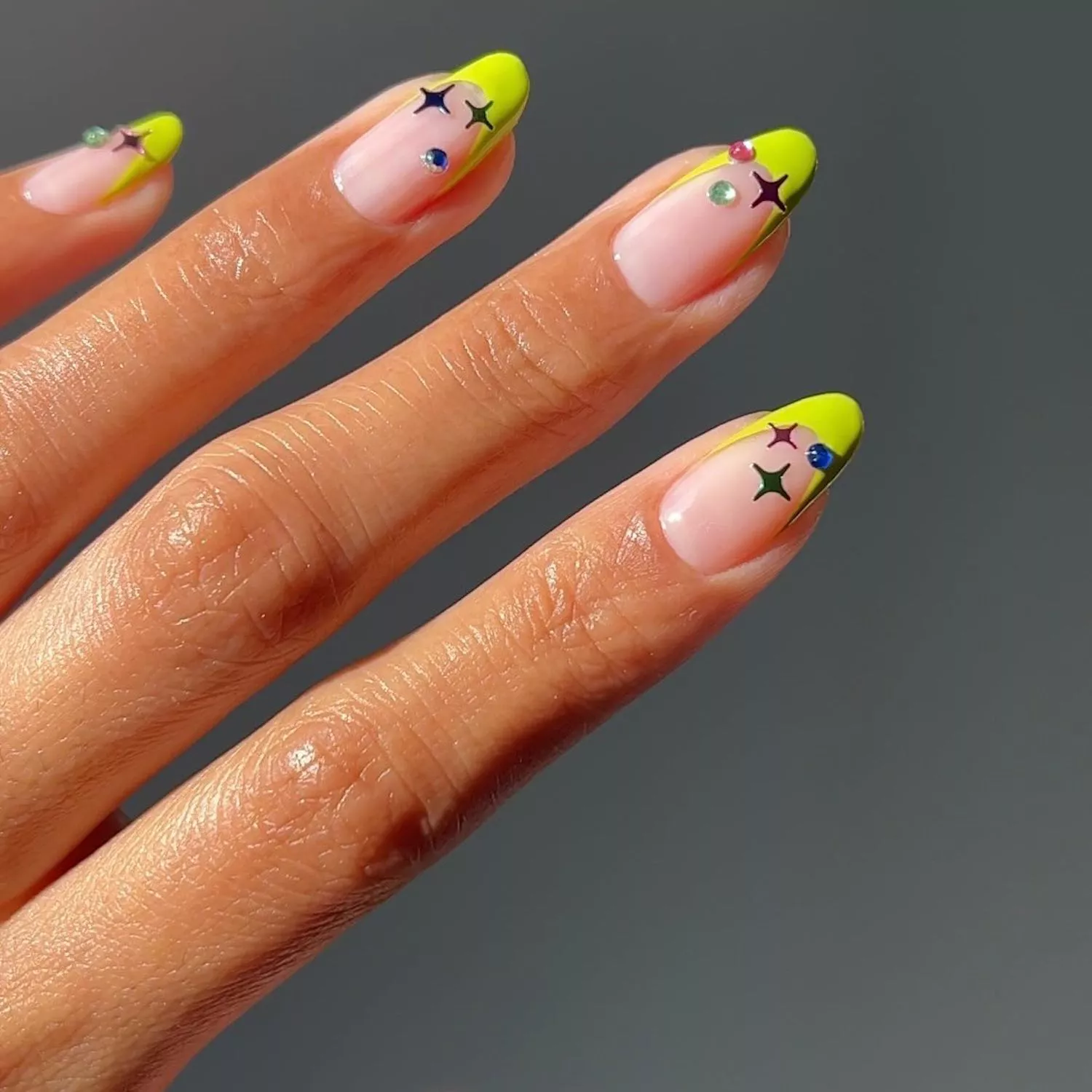 Neon yellow-green French manicure with multicolored star and gem details