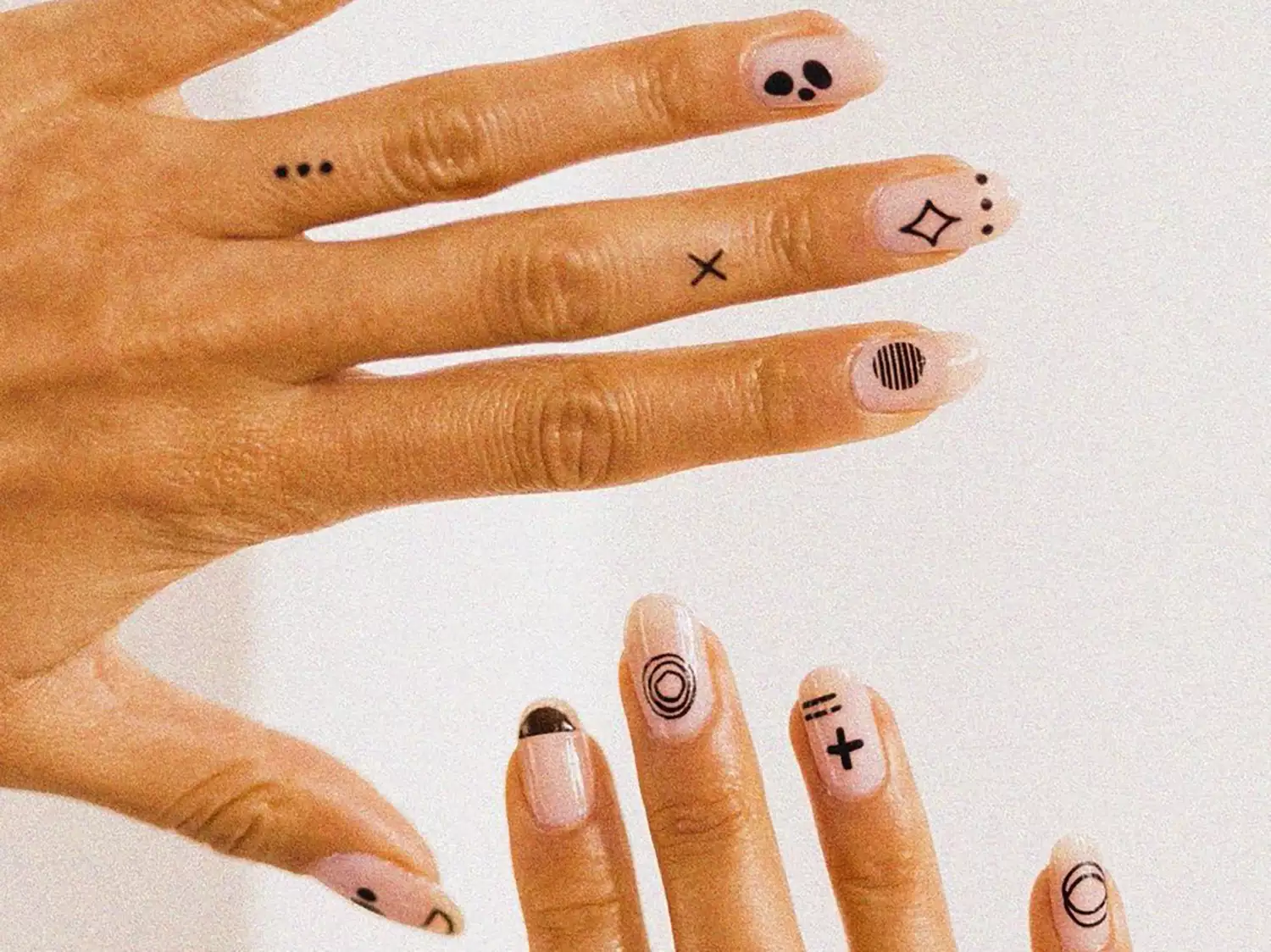 Close up of two hands with nail tattoos and finger tattoos