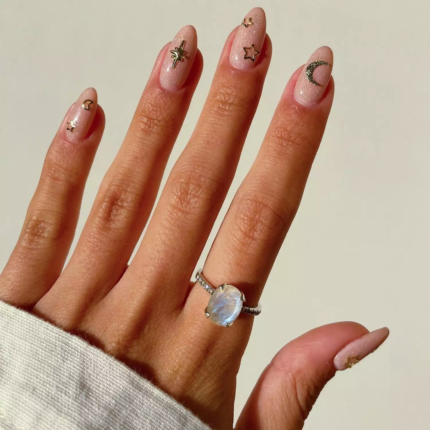 Pale pink shimmer manicure with chrome star and moon designs