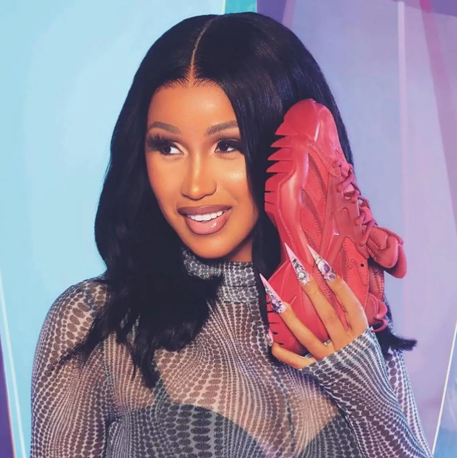 Close up of rapper Cardi B holding a sneaker to her face, with long stiletto nails