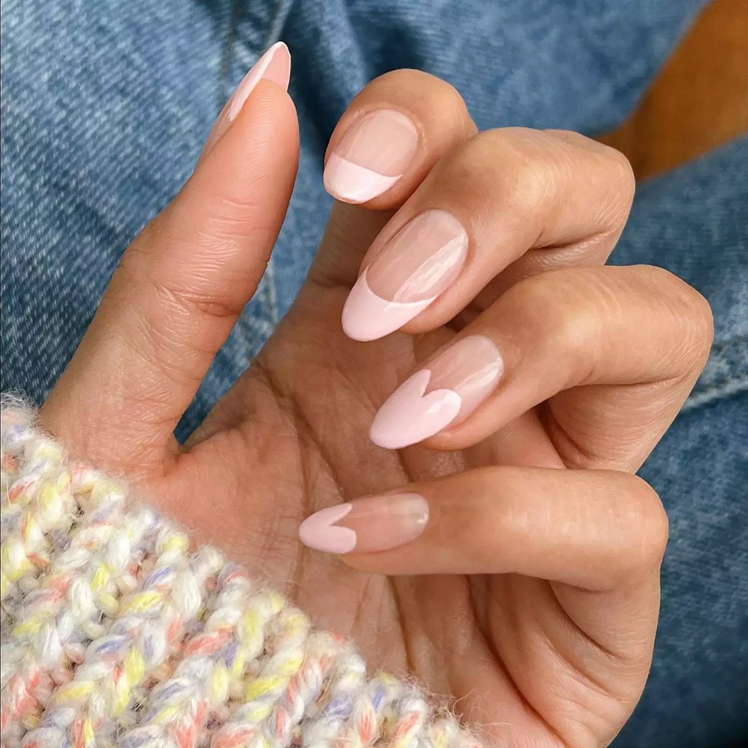 close up of a French manicure in very pale pink, with heart shaped tips on some nails