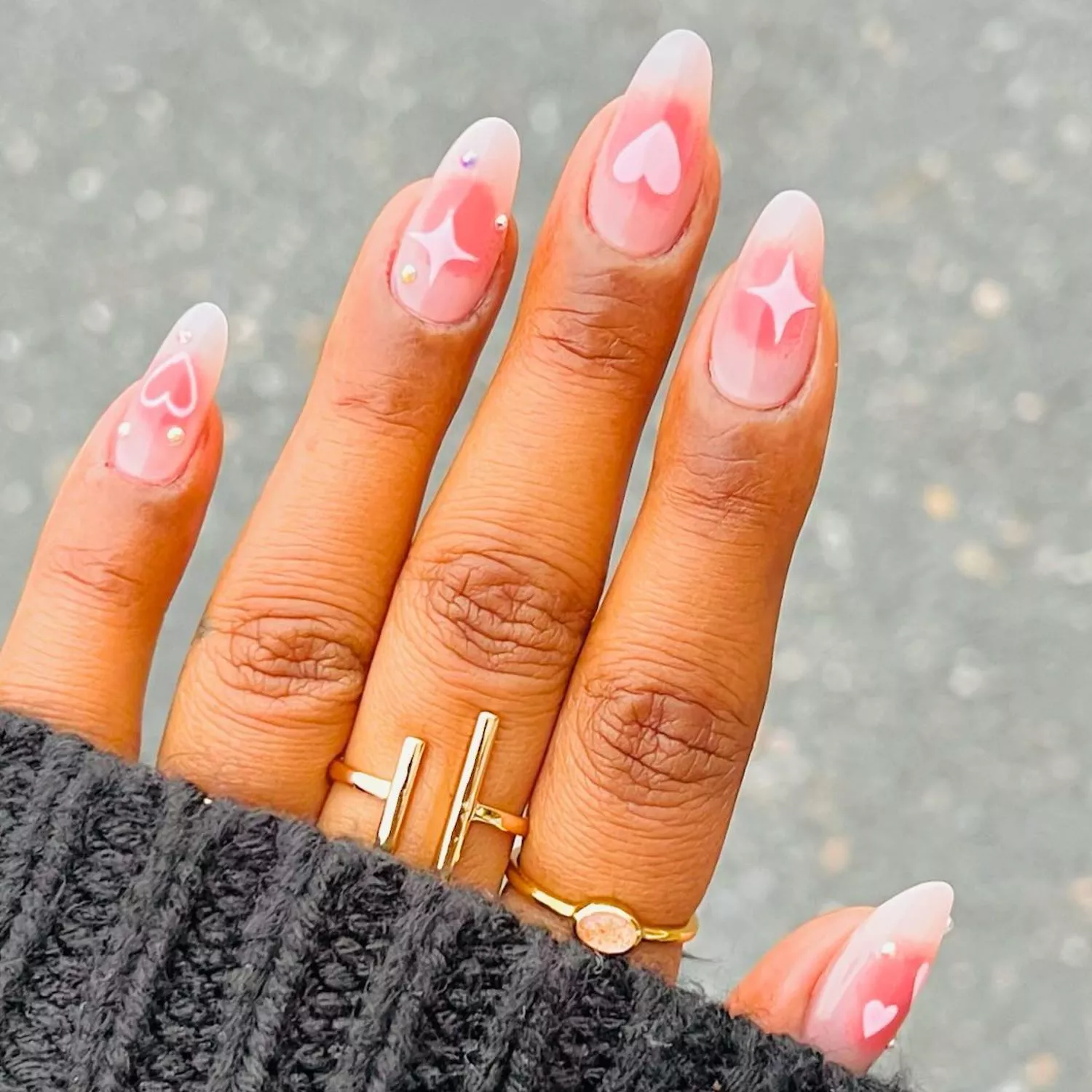 Manicure with blush effect base, heart and sparkle designs, and micro pearls