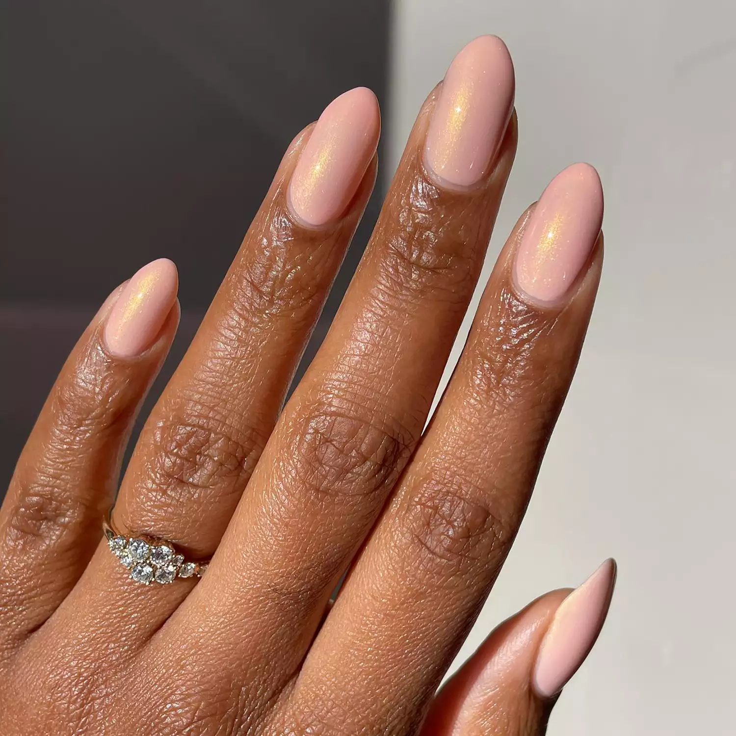 Close up of a peachy-pink manicure with gold shimmer