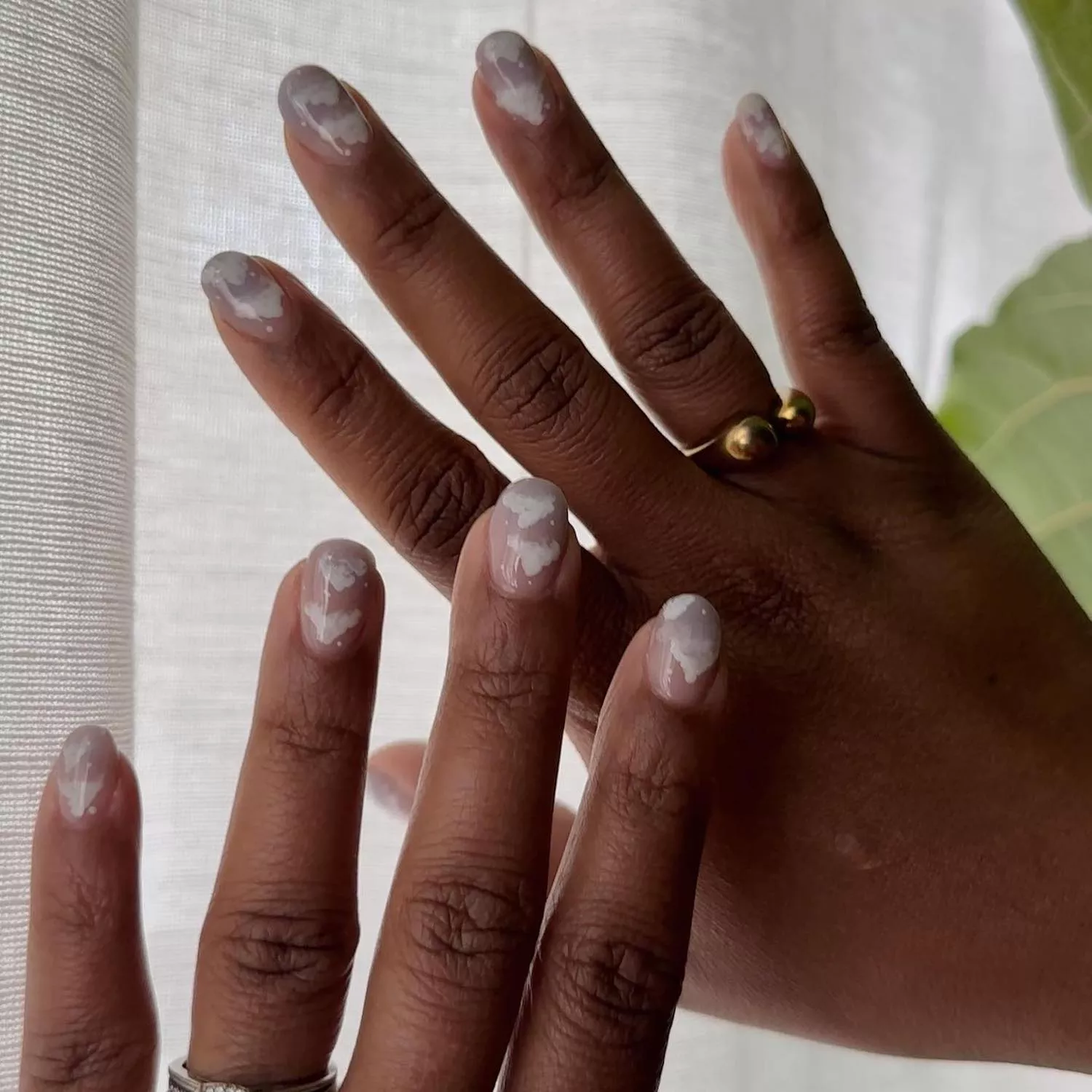 Manicure with translucent gray and nude base and cloud designs