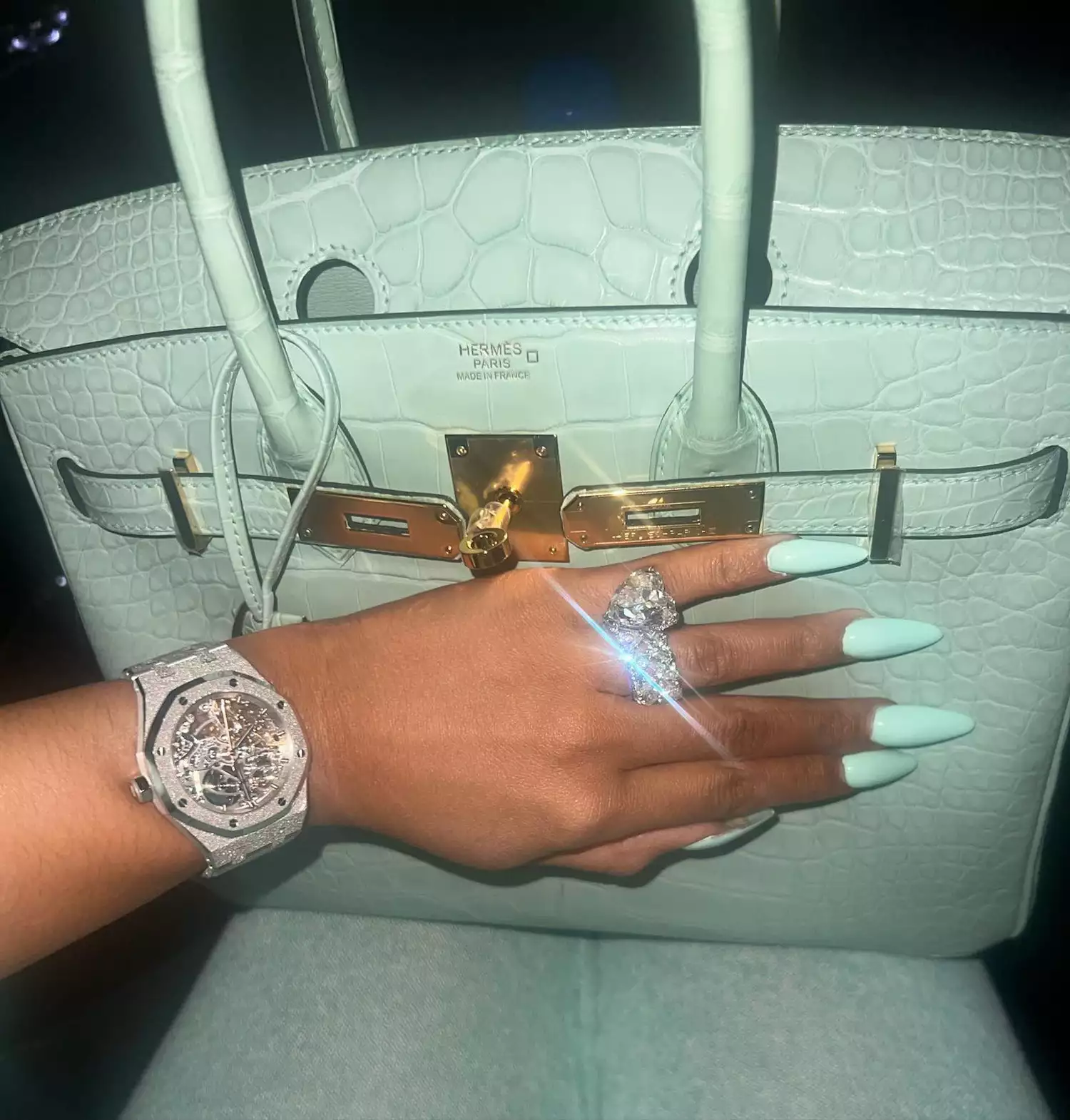 Close up of Cardi B's hand with a mint manicure, in front of a mint Hermes bag