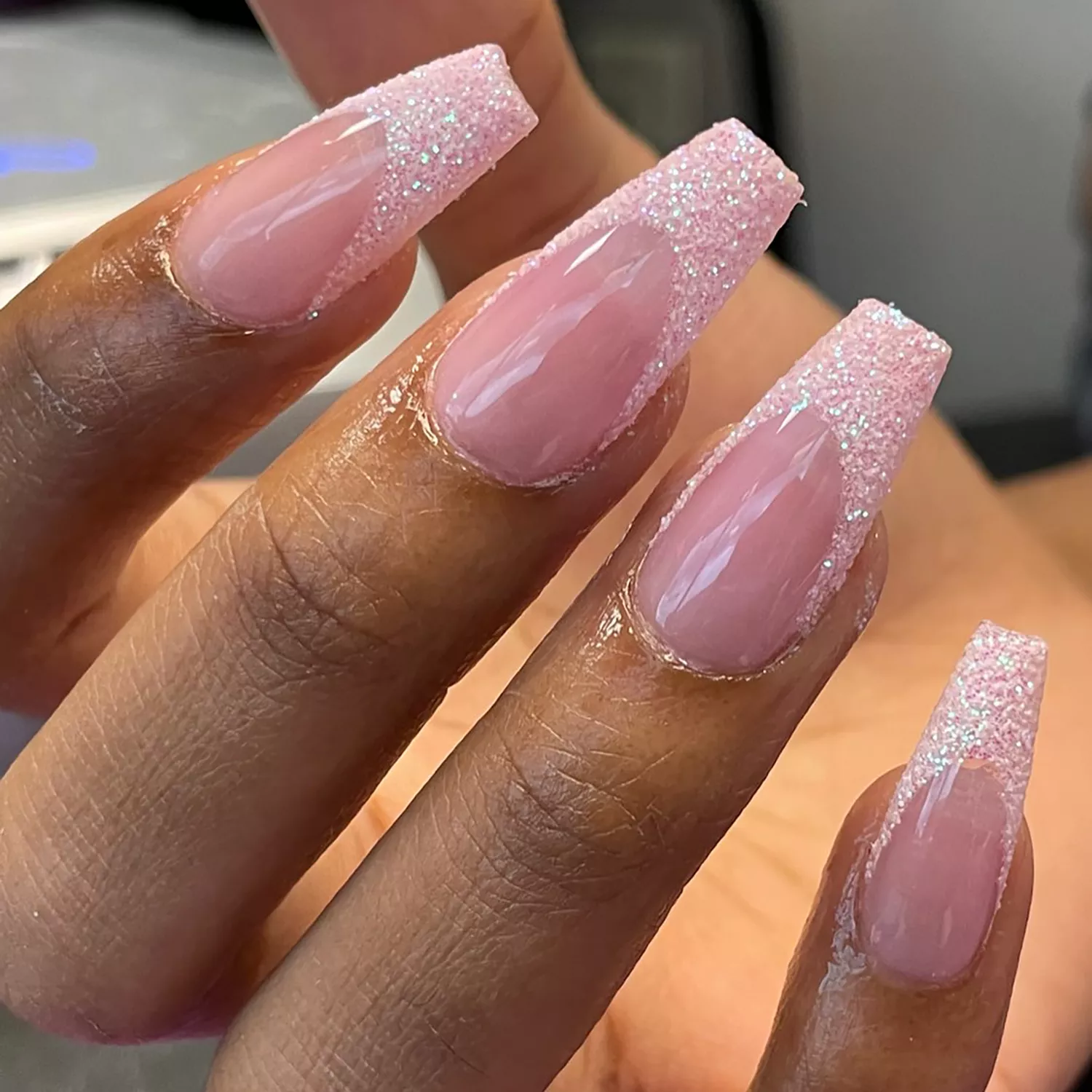 Close up of a square pink French mani with glittery tips