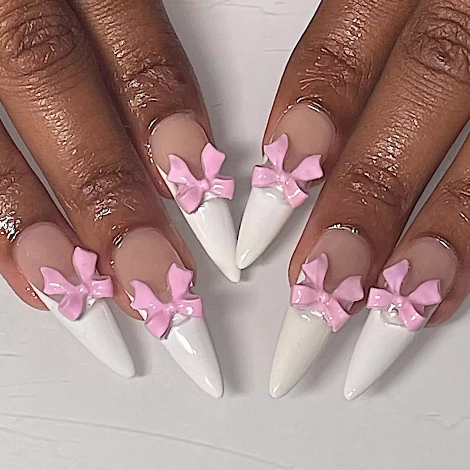 Close up of two hands, the nails with white French tips and 3D pink bows