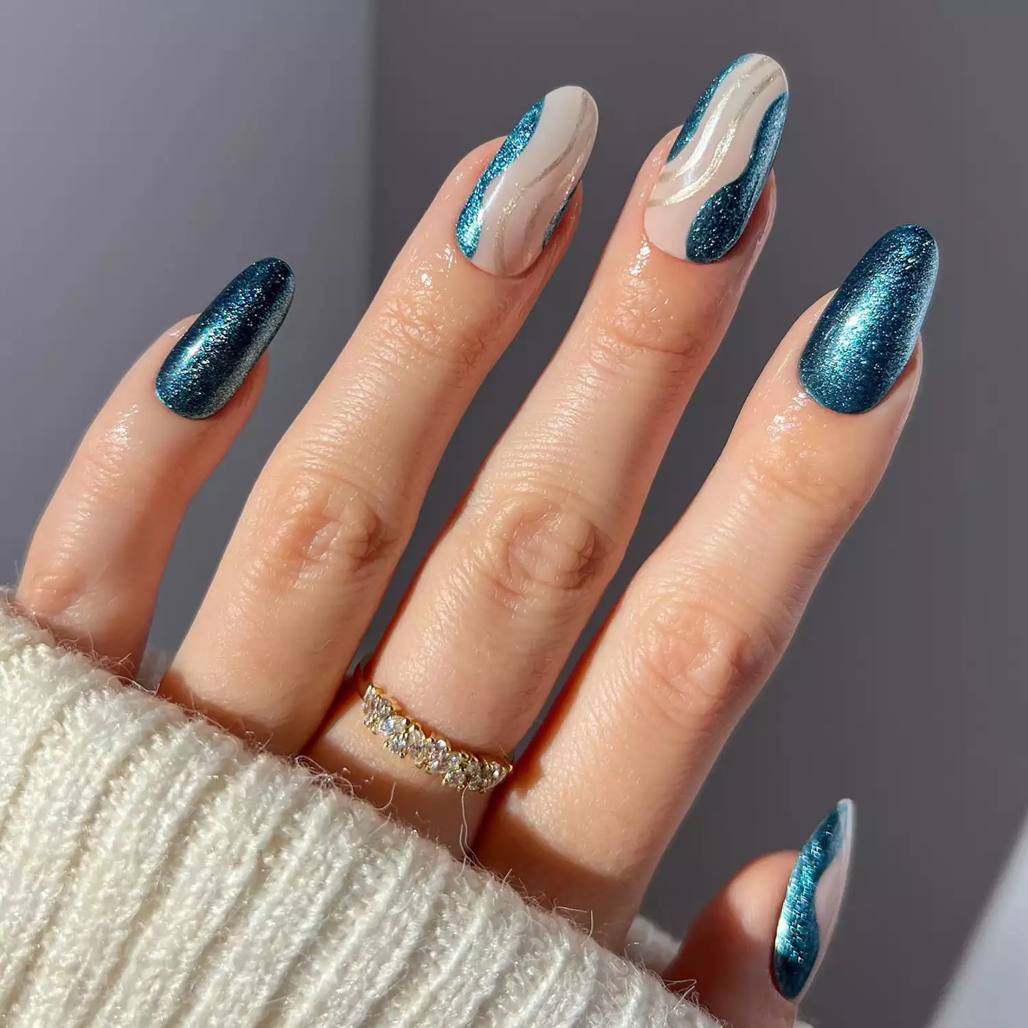 Close up of a glittery blue manicure with swirl nail art