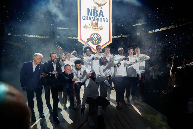 Oct. 24: Denver Nuggets players and team personnel pose for a picture as their NBA championship banner is lifted into the rafters before the season opener against the Los Angeles Lakers.