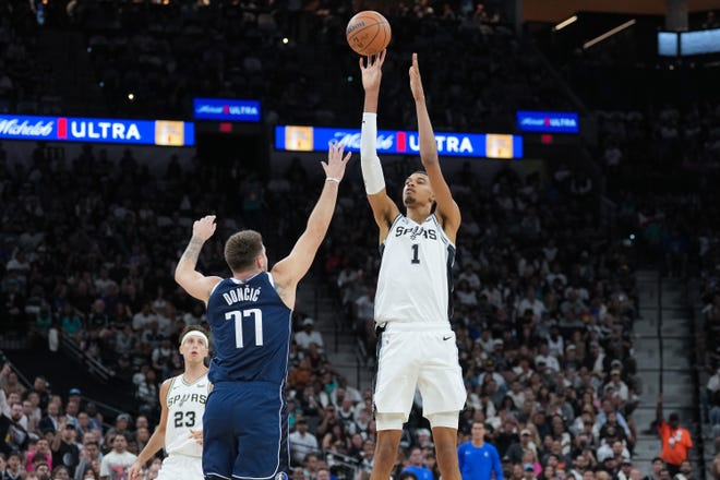 Oct. 25: San Antonio Spurs center Victor Wembanyama (1) shoots over Dallas Mavericks guard Luka Doncic (77) in the first half of his first NBA game.