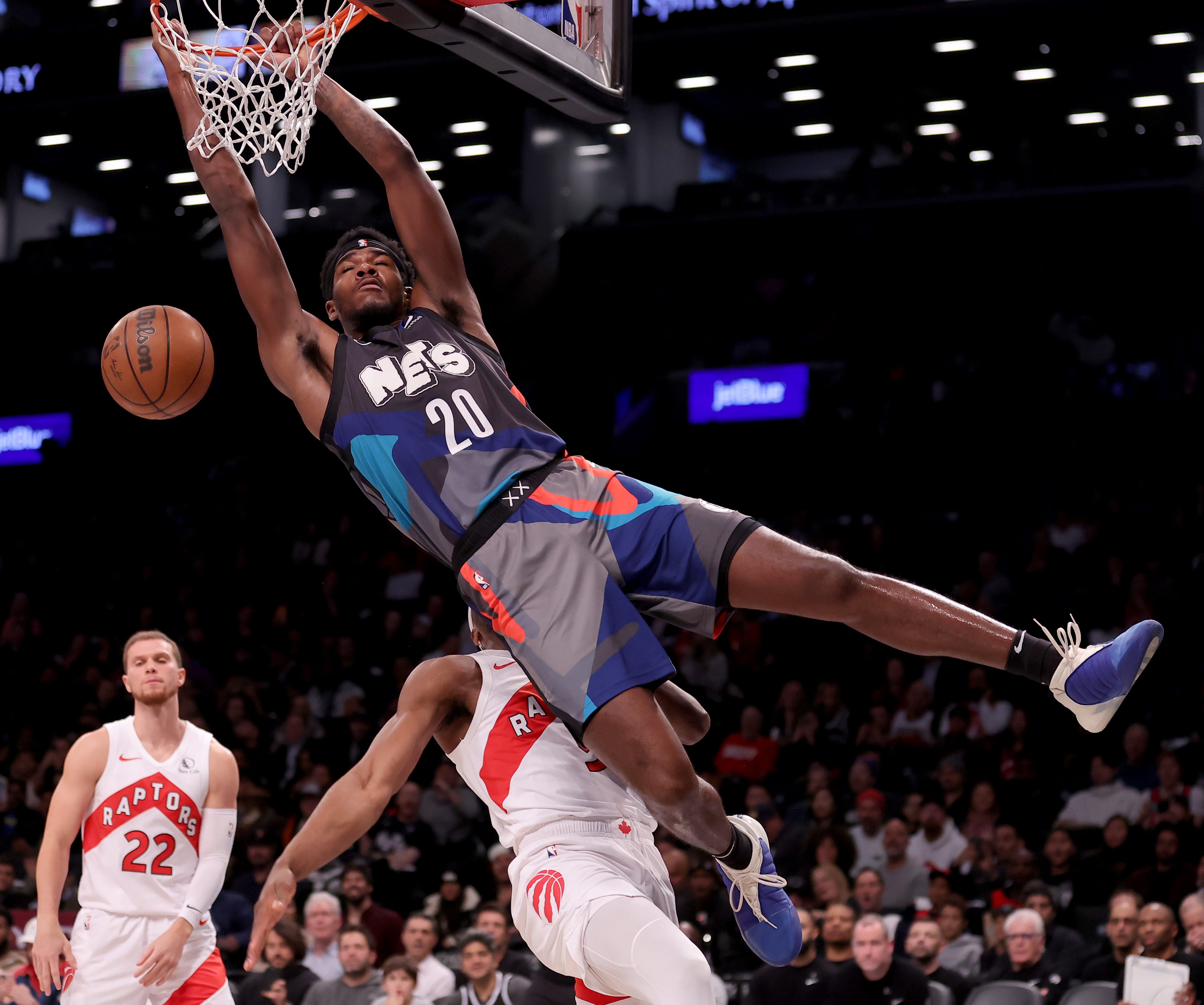 Nov. 28: The Brooklyn Nets' Day'Ron Sharpe (20) hangs on to the rim after dunking against the Toronto Raptors at Barclays Center. The Nets won the game, 115-103.