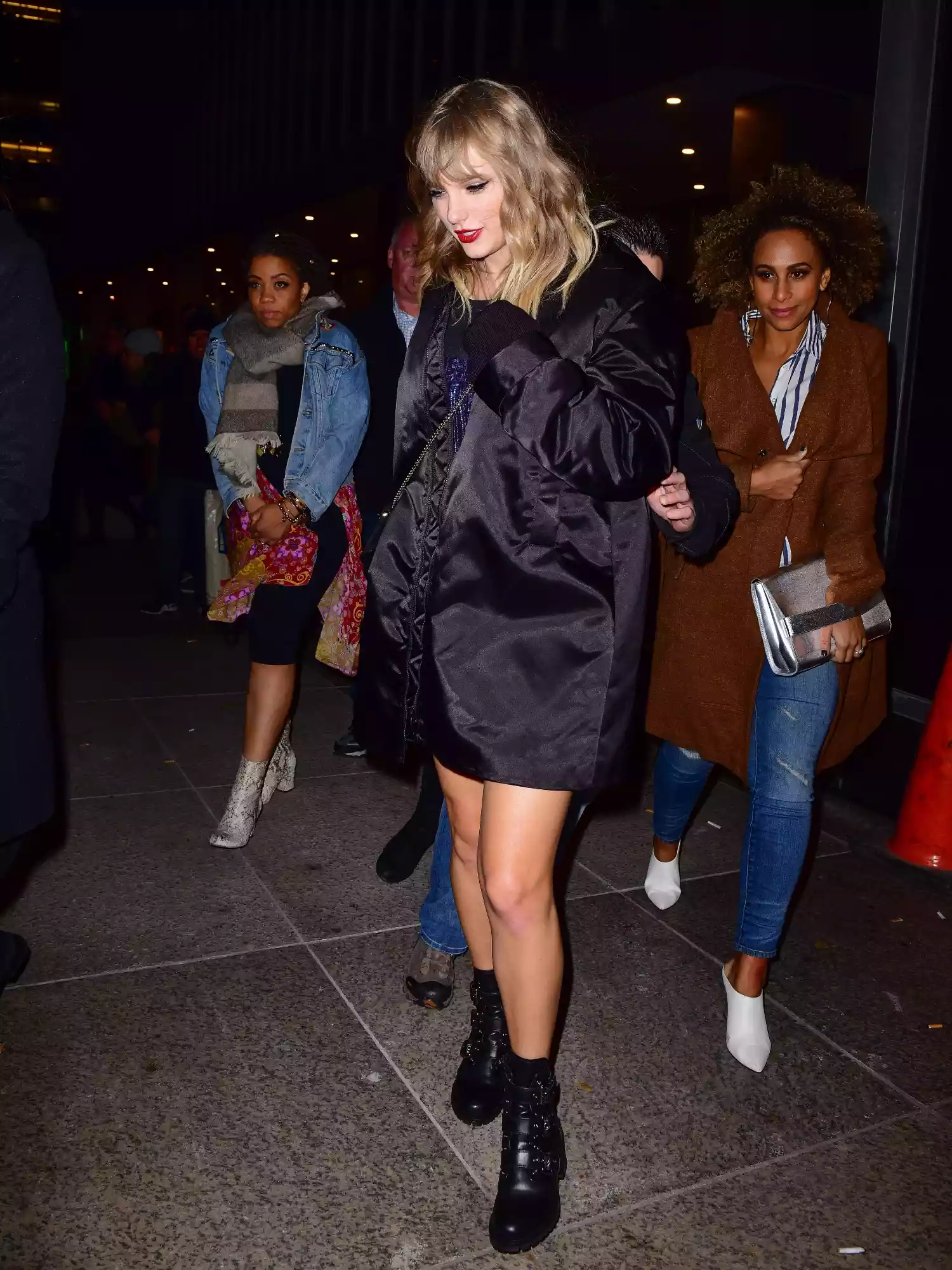 Taylor Swift wearing black boots and a black coat on the streets of New York City