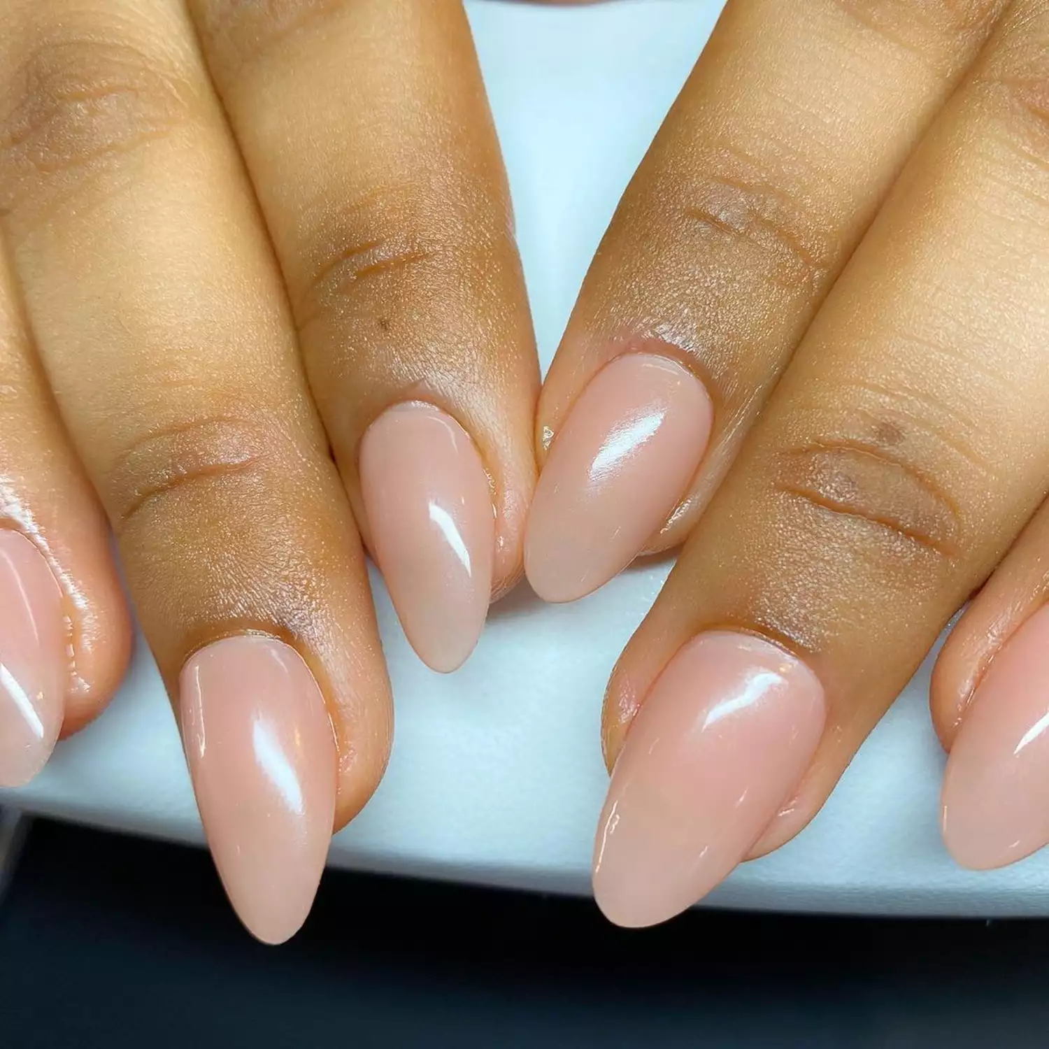 Close up of a glossy neutral manicure in an oval shape