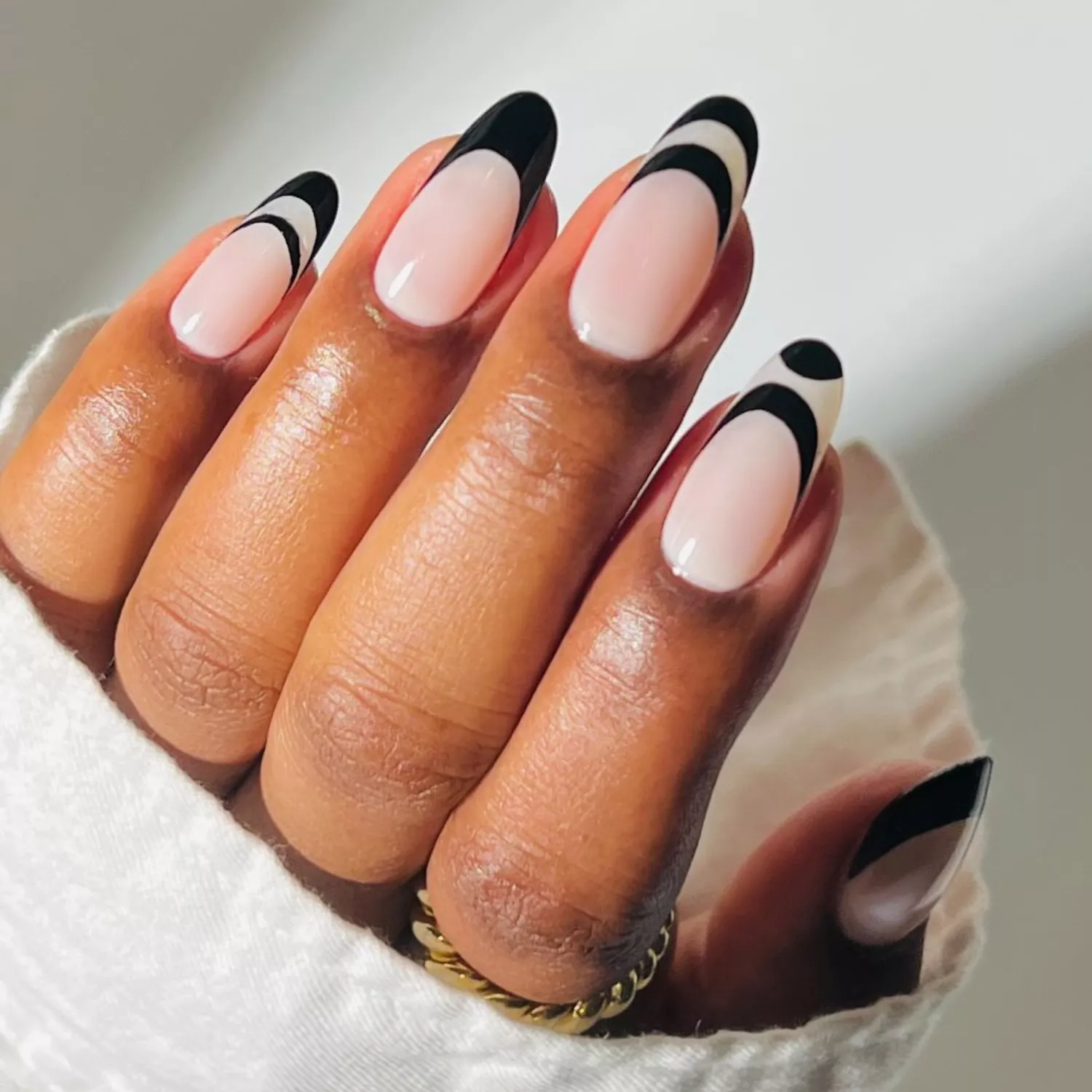 A milky neutral manicure with black designs on the tips