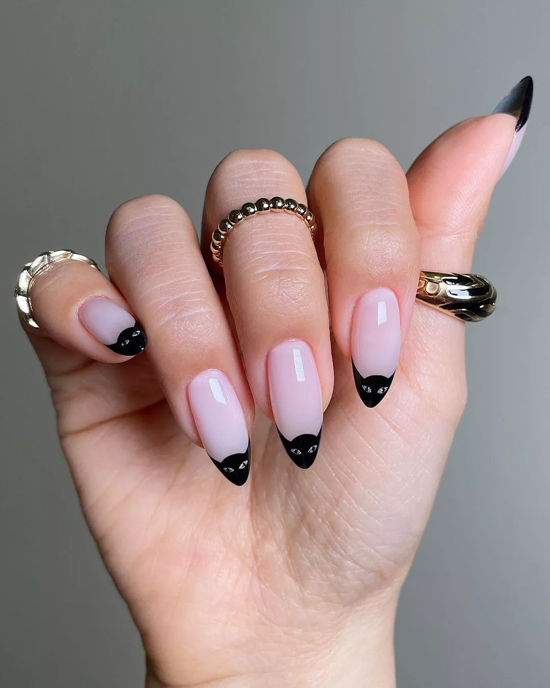 A woman wearing a simple nail design featuring the face of a black cat on the tips