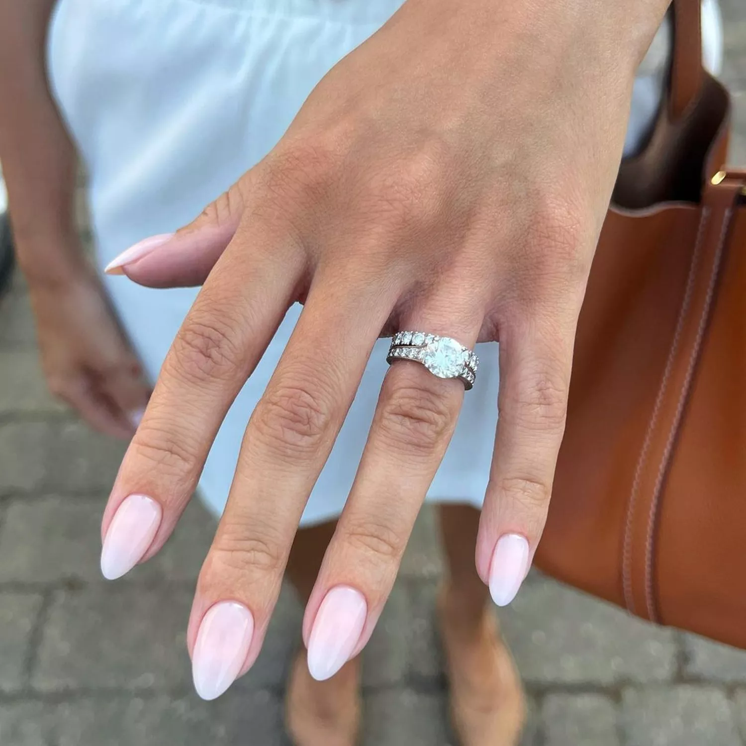 A hand with a milky-nude oval-shaped manicure 