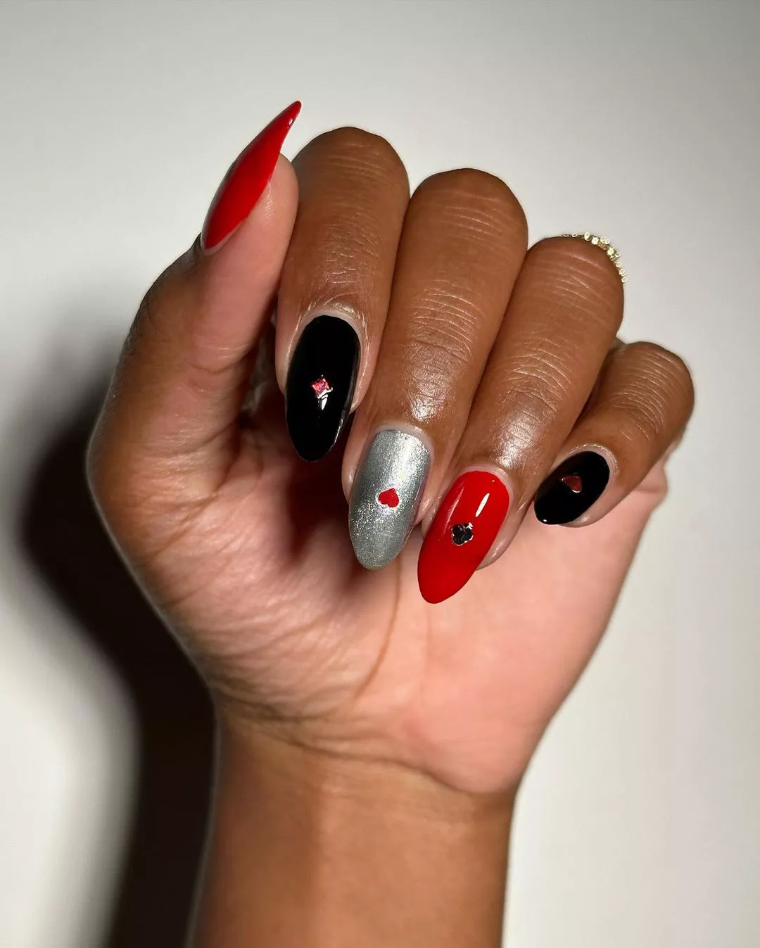 A woman wearing a simple nail design featuring black, red, and silver