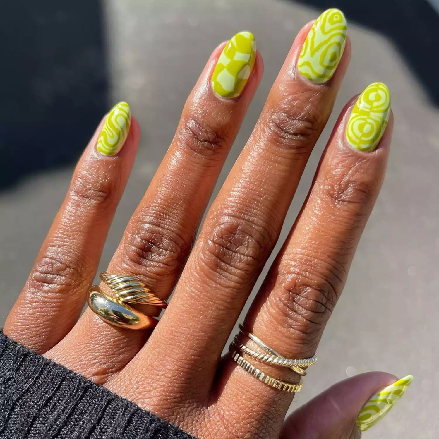 Chartreuse Swirl Mismatched Nails, with concrete out of focus in the background