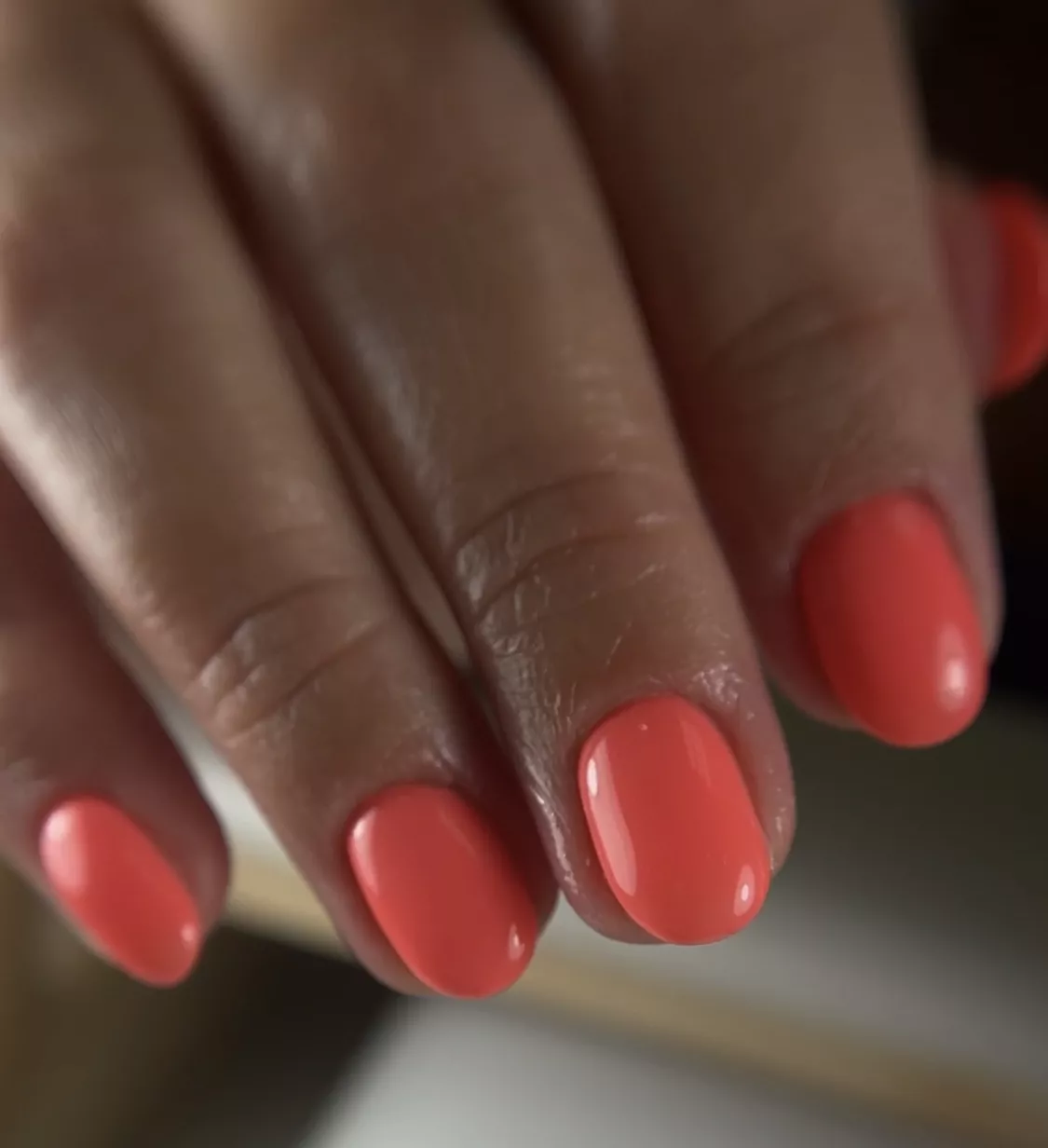 A woman wearing a simple nail design featuring scarlet red