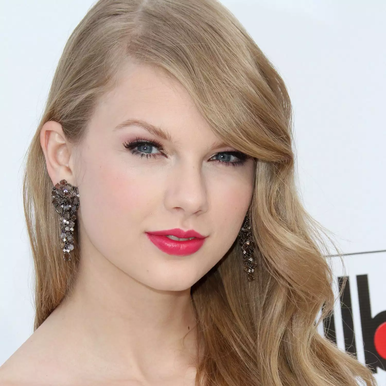 Taylor Swift wears soft curls with a deep side part and red lipstick to the 2011 Billboard Music Awards