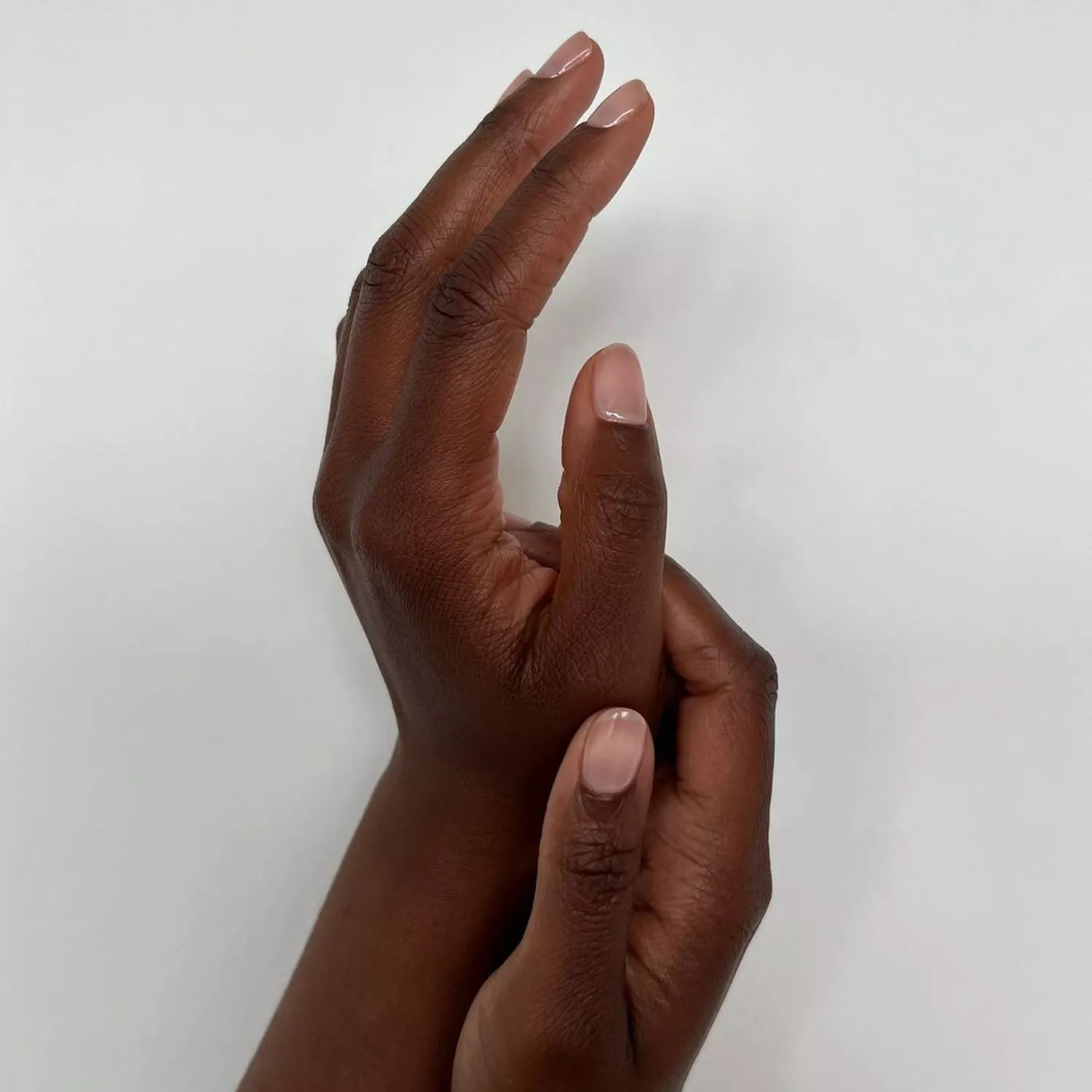 Two hands viewed from the side, glossy thumbs visible