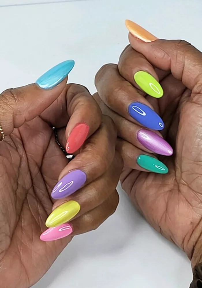 A woman wearing a simple nail design featuring a different color on each nail