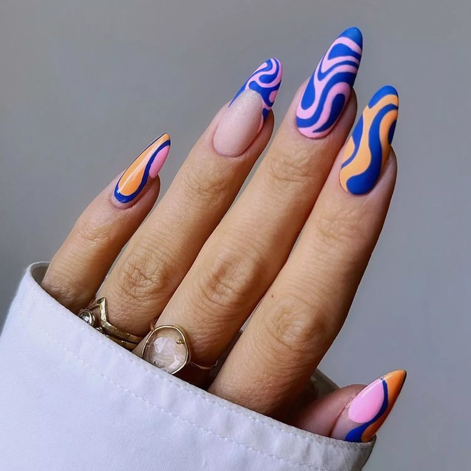 Matte Contrast Swirl Nails in shades of blue, pink, and orange, against a gray background