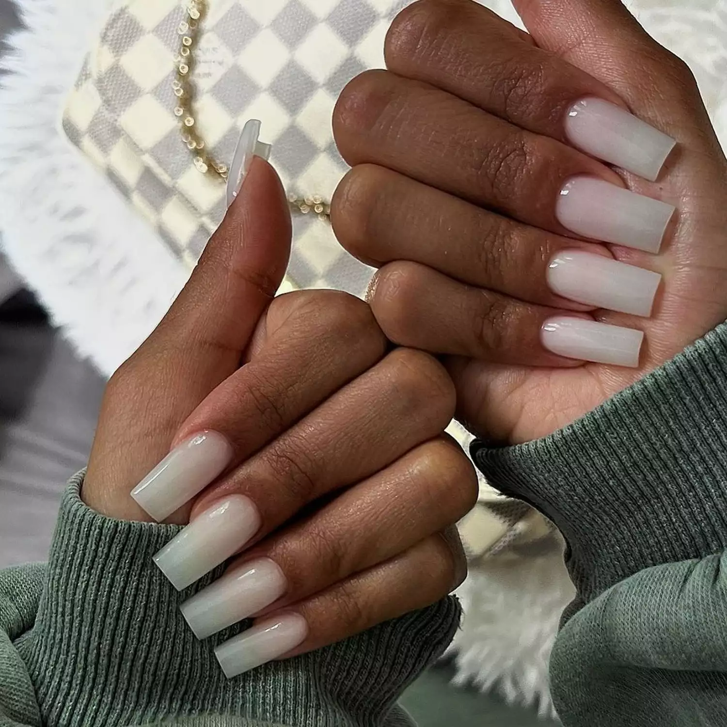 Fingers folded over into the palm, a milky, square manicure on the fingers