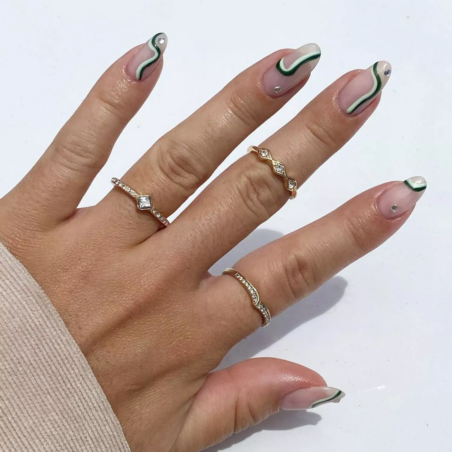 Minimalist Green Swirl Nails with a milky base, against a white background