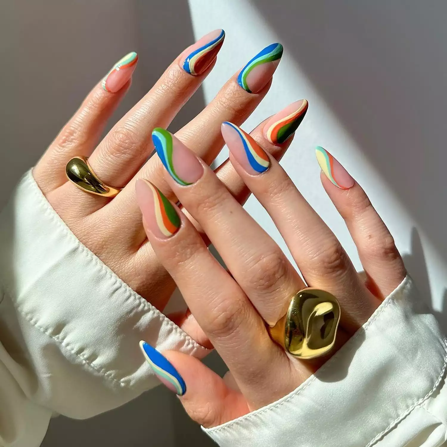 A multicolor Swirl Negative Space manicure against a white background