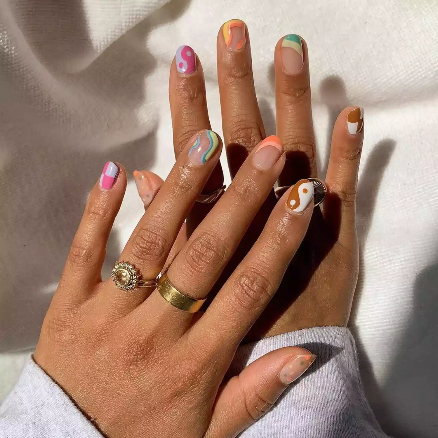 Manicure with pastel yin/yang, abstract negative space, checkerboard, yin/yang, and dot designs