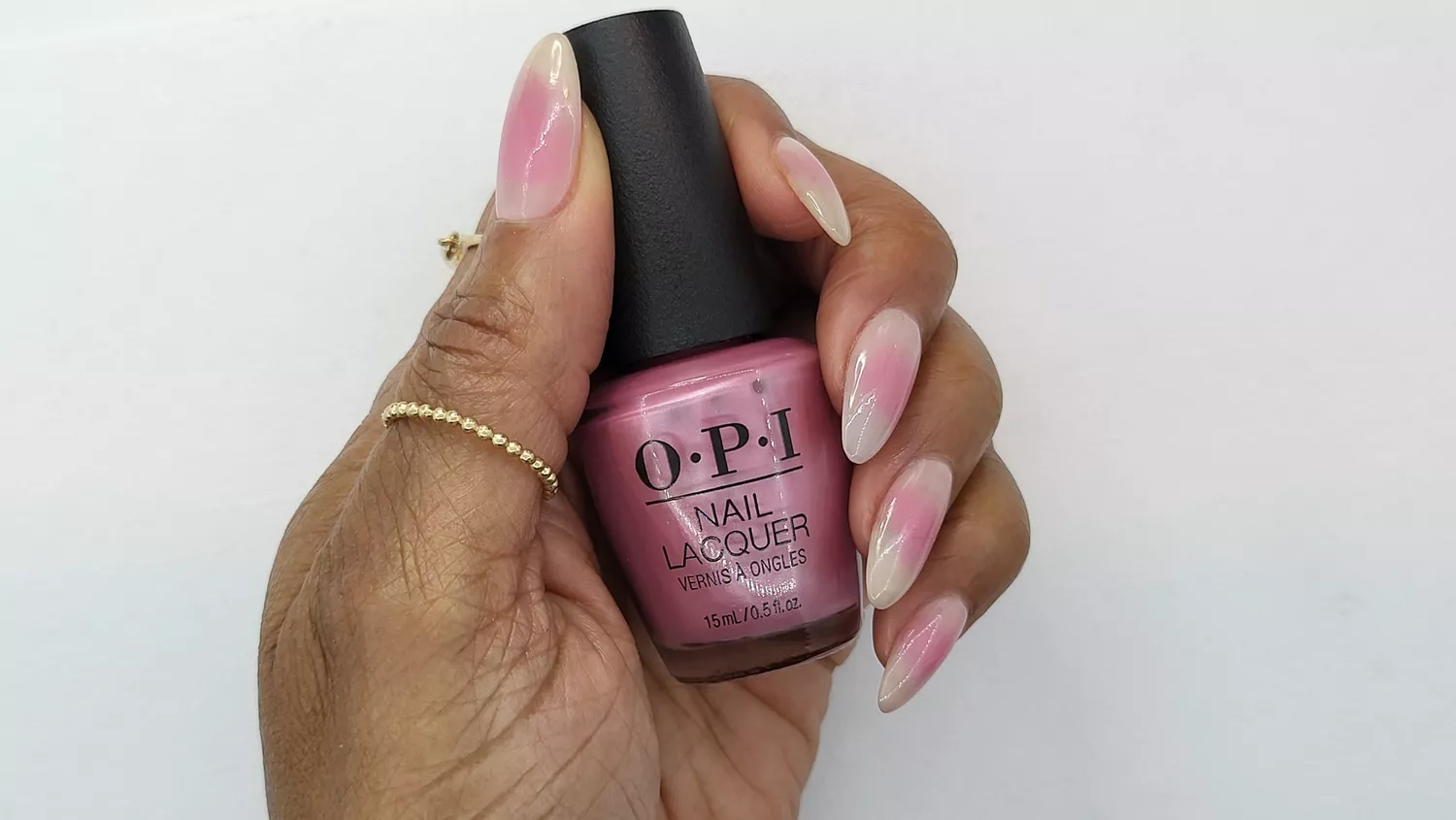 A woman wearing a simple nail design featuring a sheer pink focal point