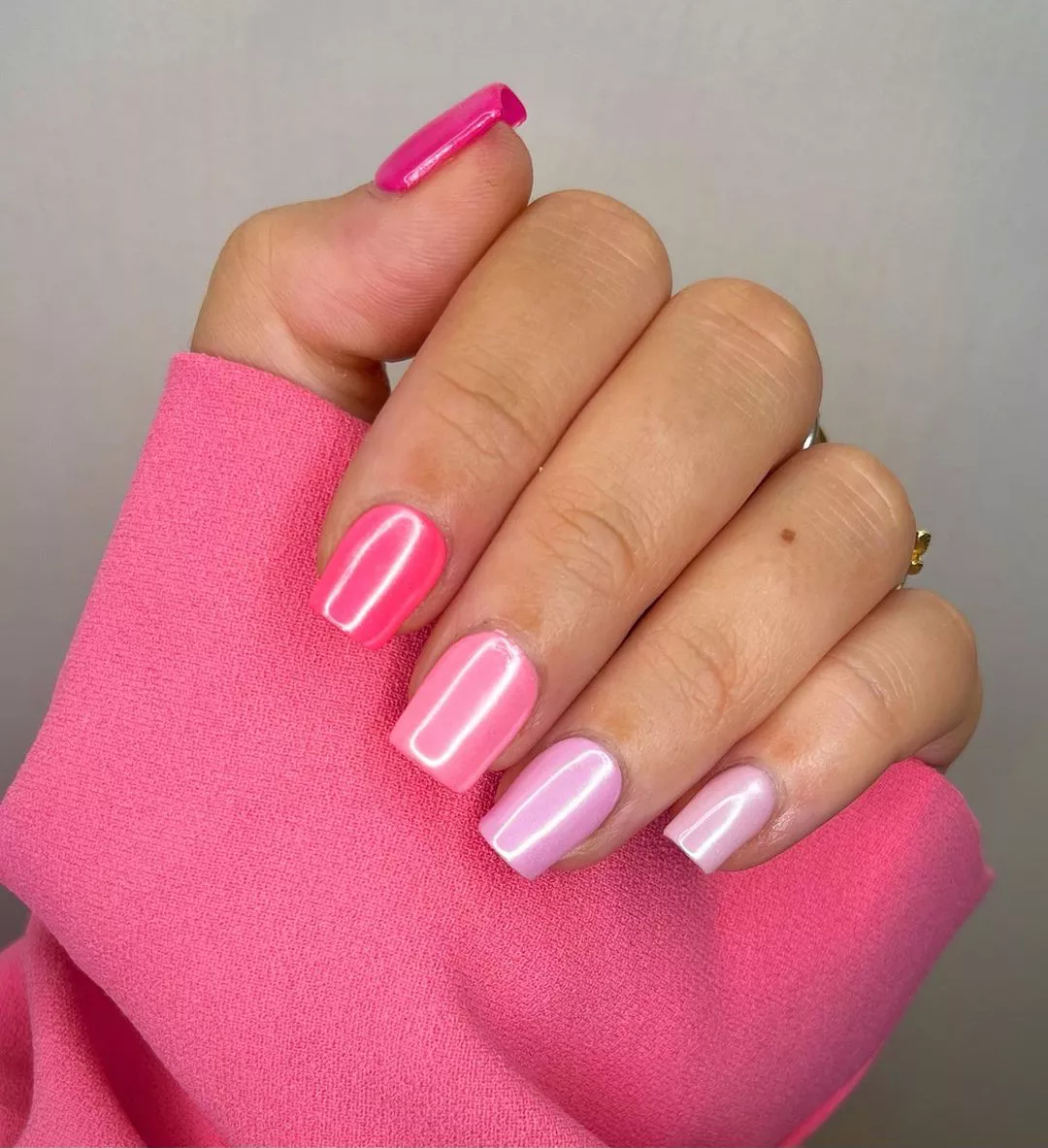 A woman wearing a simple nail design featuring shades of pink