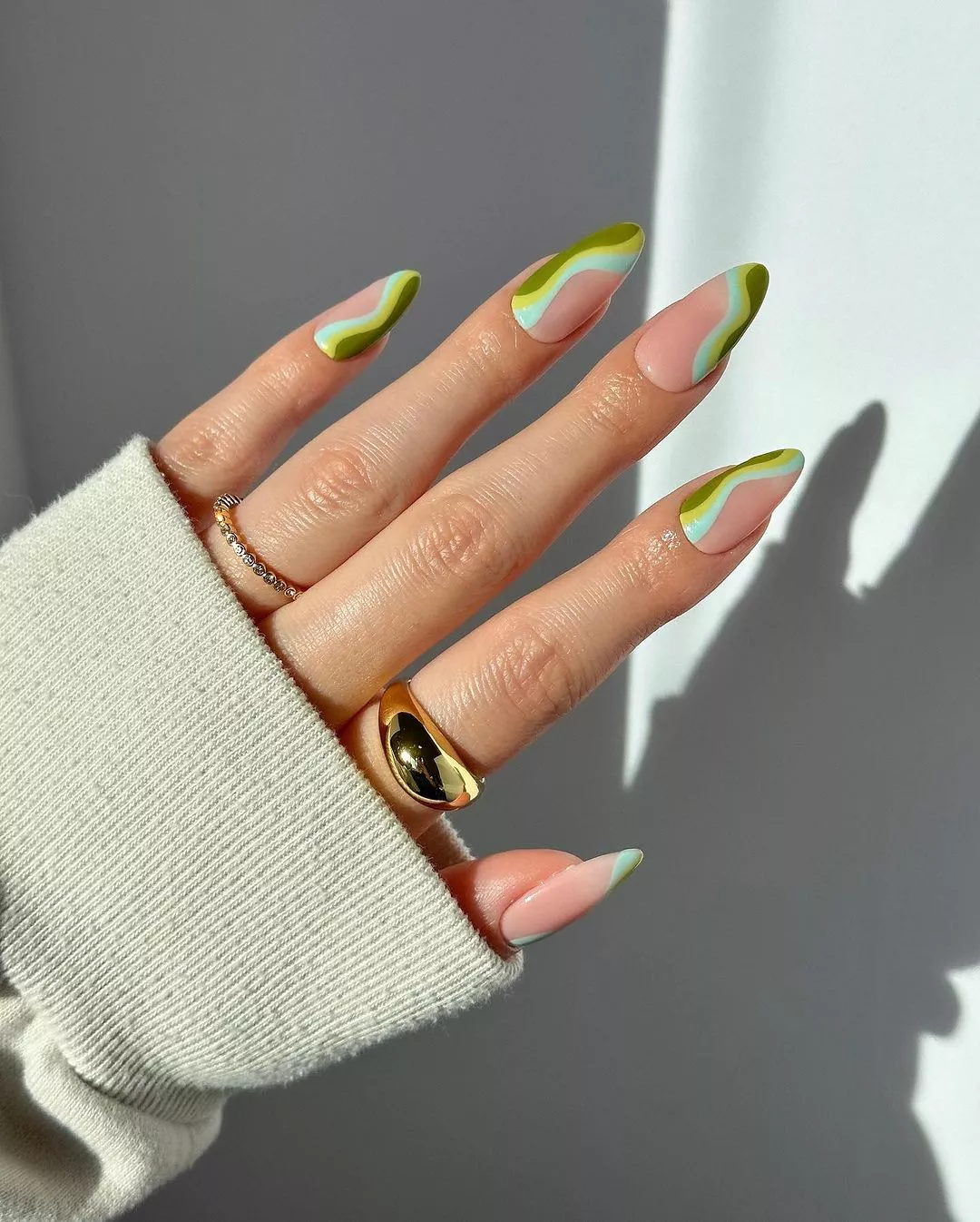 A woman wearing a simple nail design featuring green lines 