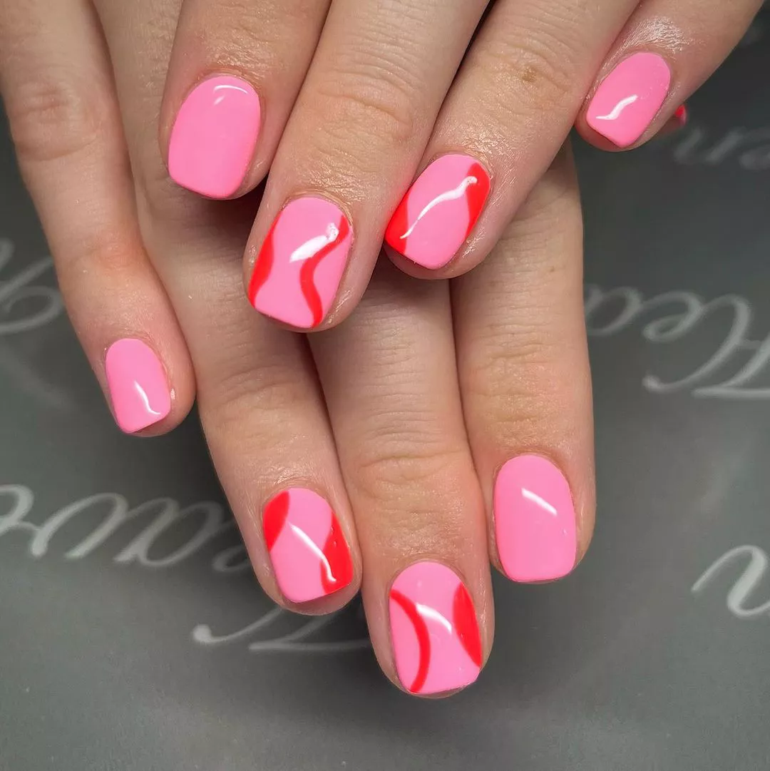 A woman wearing a simple nail design featuring red abstract lines and shapes