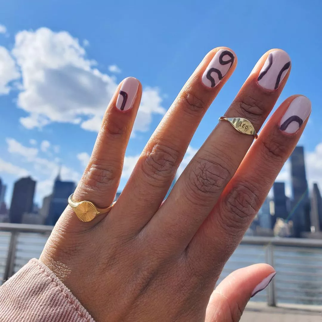 A woman wearing a simple nail design featuring purple squiggles