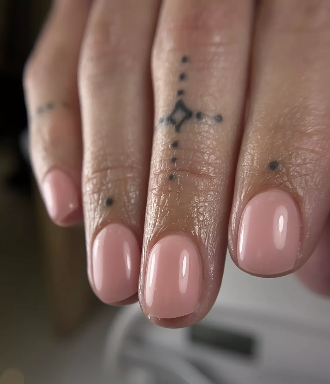 A woman wearing a simple nail design featuring a pink, milky shade