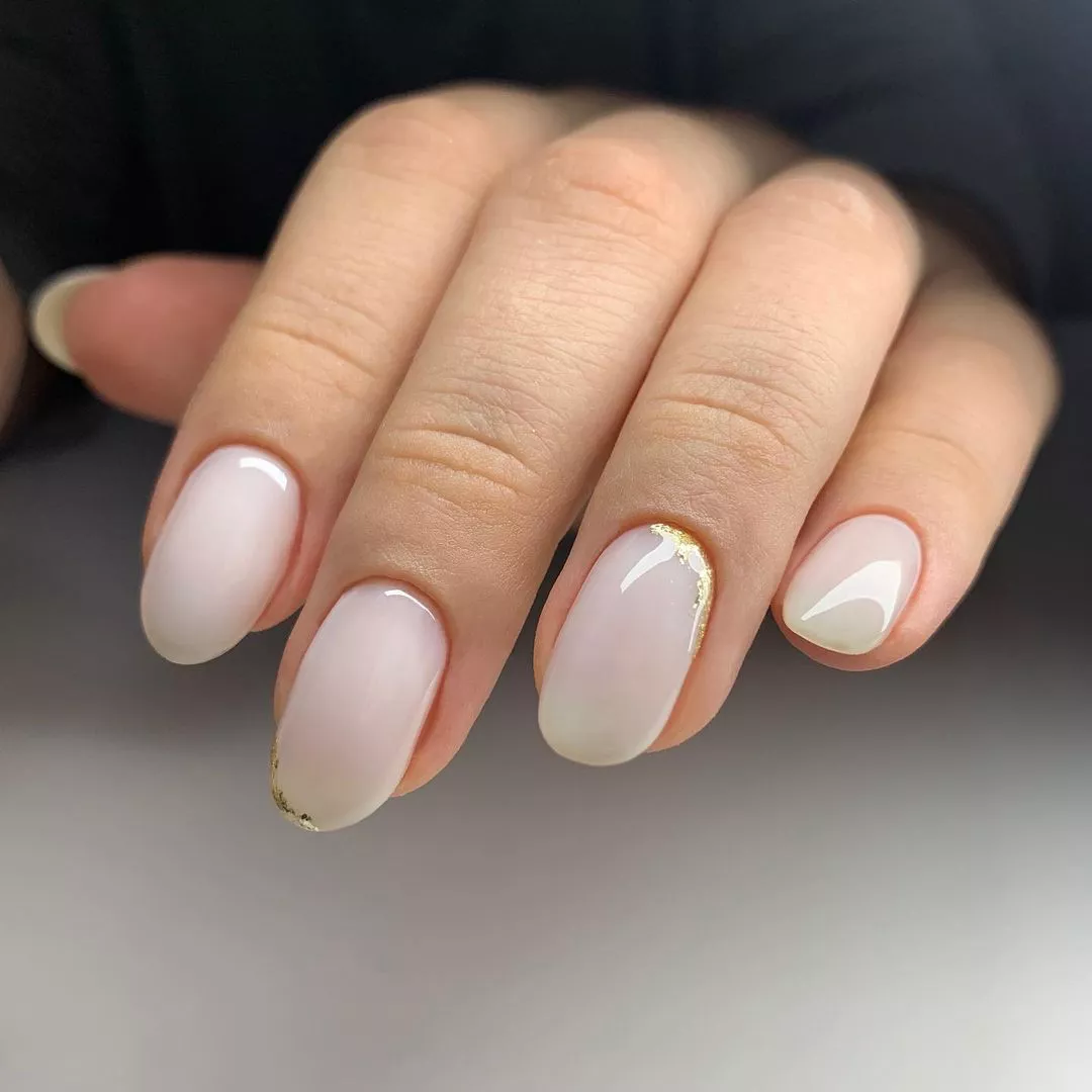 A woman wearing a simple nail design featuring a bit of gold glitter