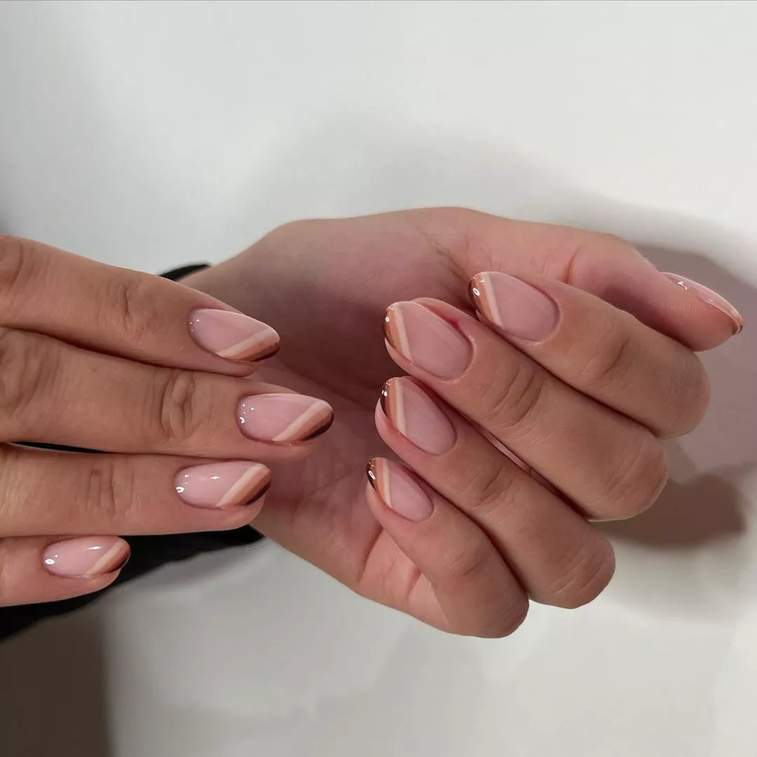 A woman wearing a simple nail design featuring brown lines on the tips