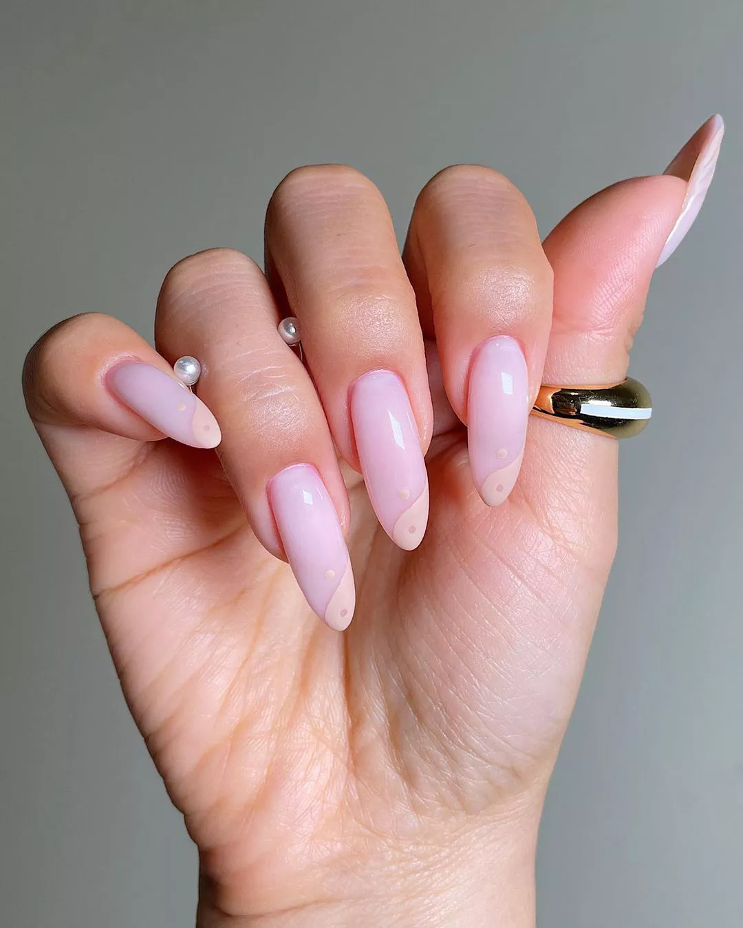 A woman wearing a simple nail design featuring a peach Ying and Yang tip